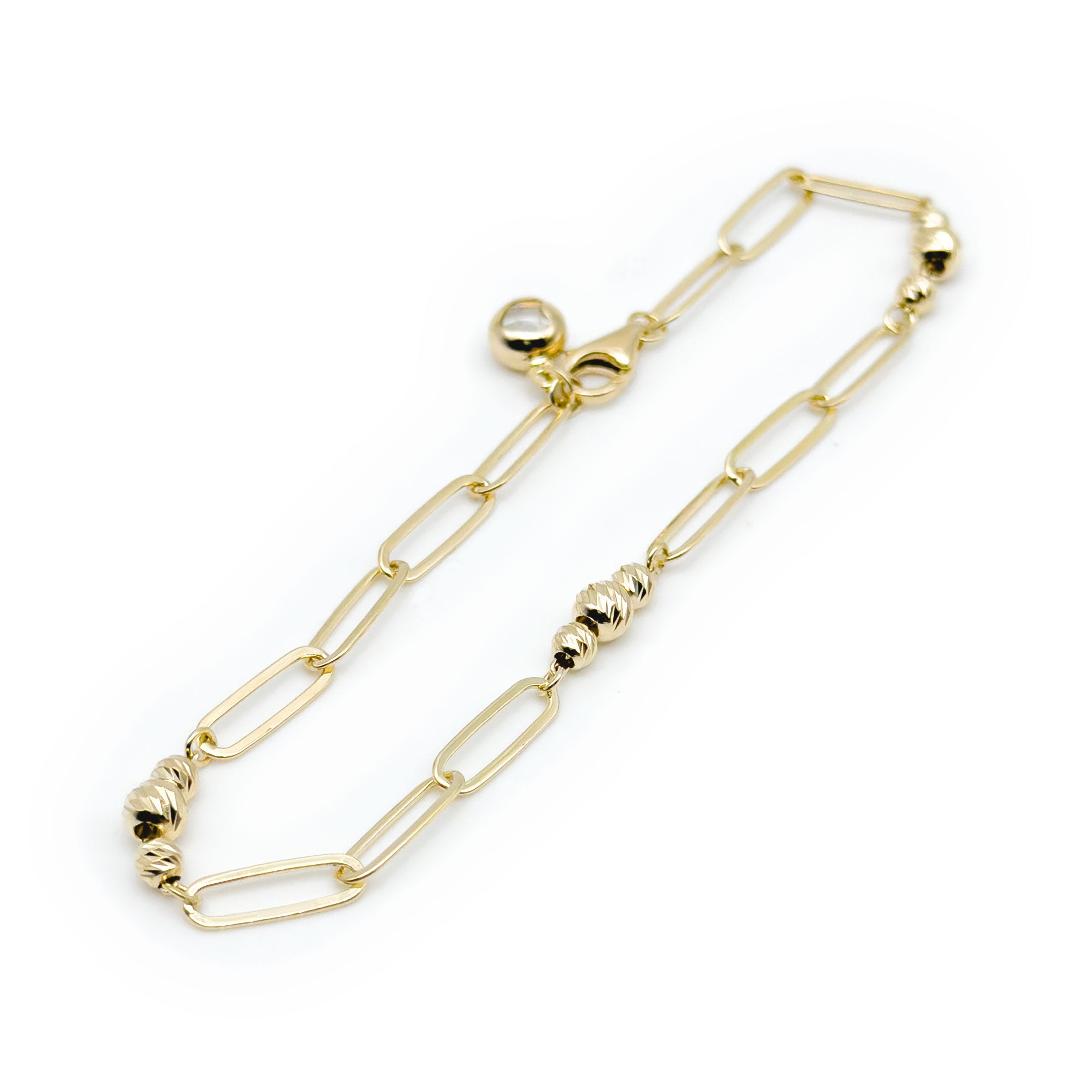 A gold paperclip chain bracelet with small textured bead accents, displayed on a clean white background. close