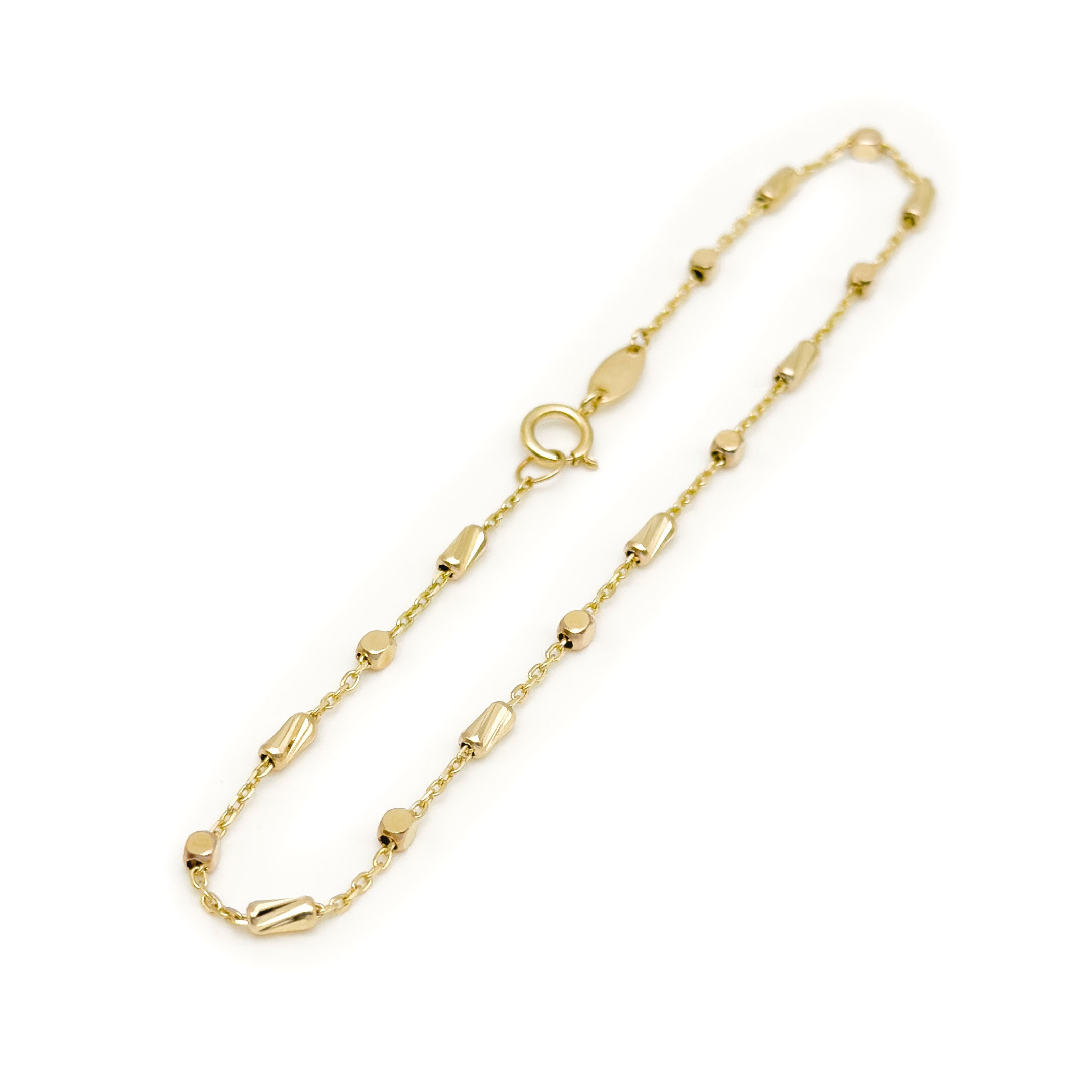 A delicate yellow gold bracelet with small polished bead-like links and elongated cylinder accents, displayed on a clean white background. close up