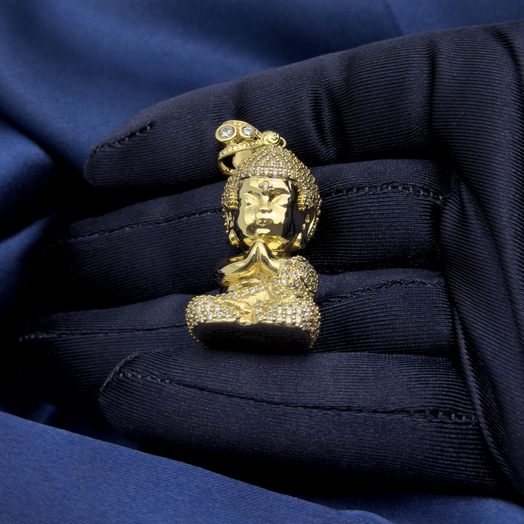 10k Yellow Gold Baby Buddha Full Body Pendant with CZ Stones on blue background in hand