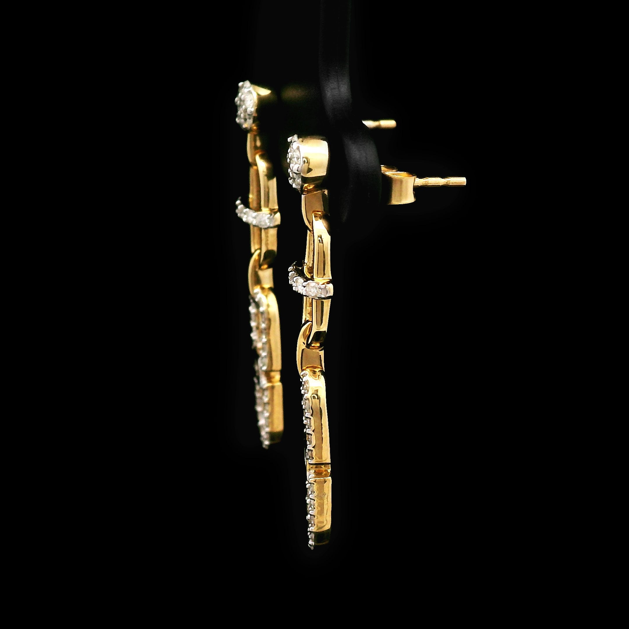 Pair of 14k gold and diamond earrings on a black background with cable design side