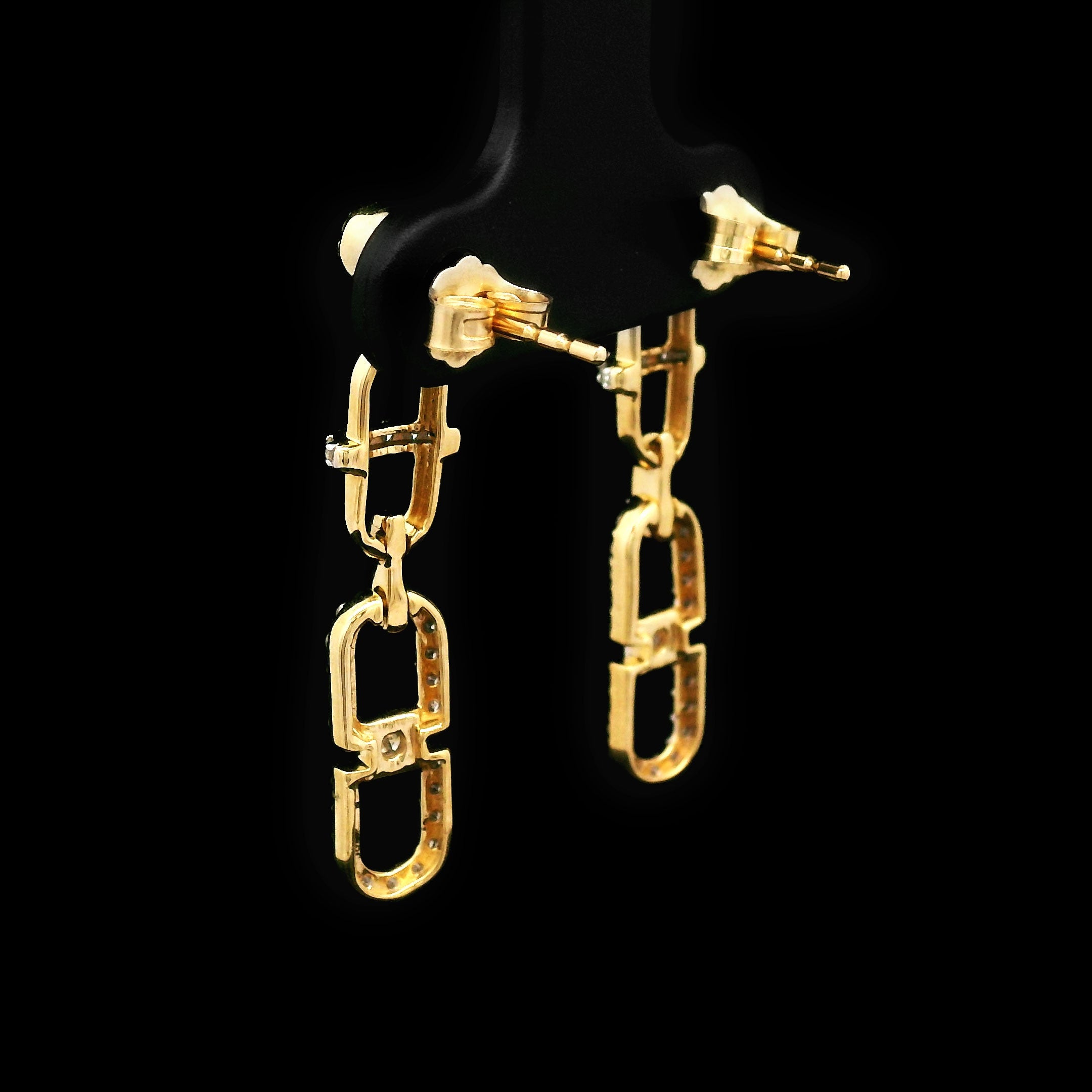 Pair of 14k gold and diamond earrings on a black background with cable design back