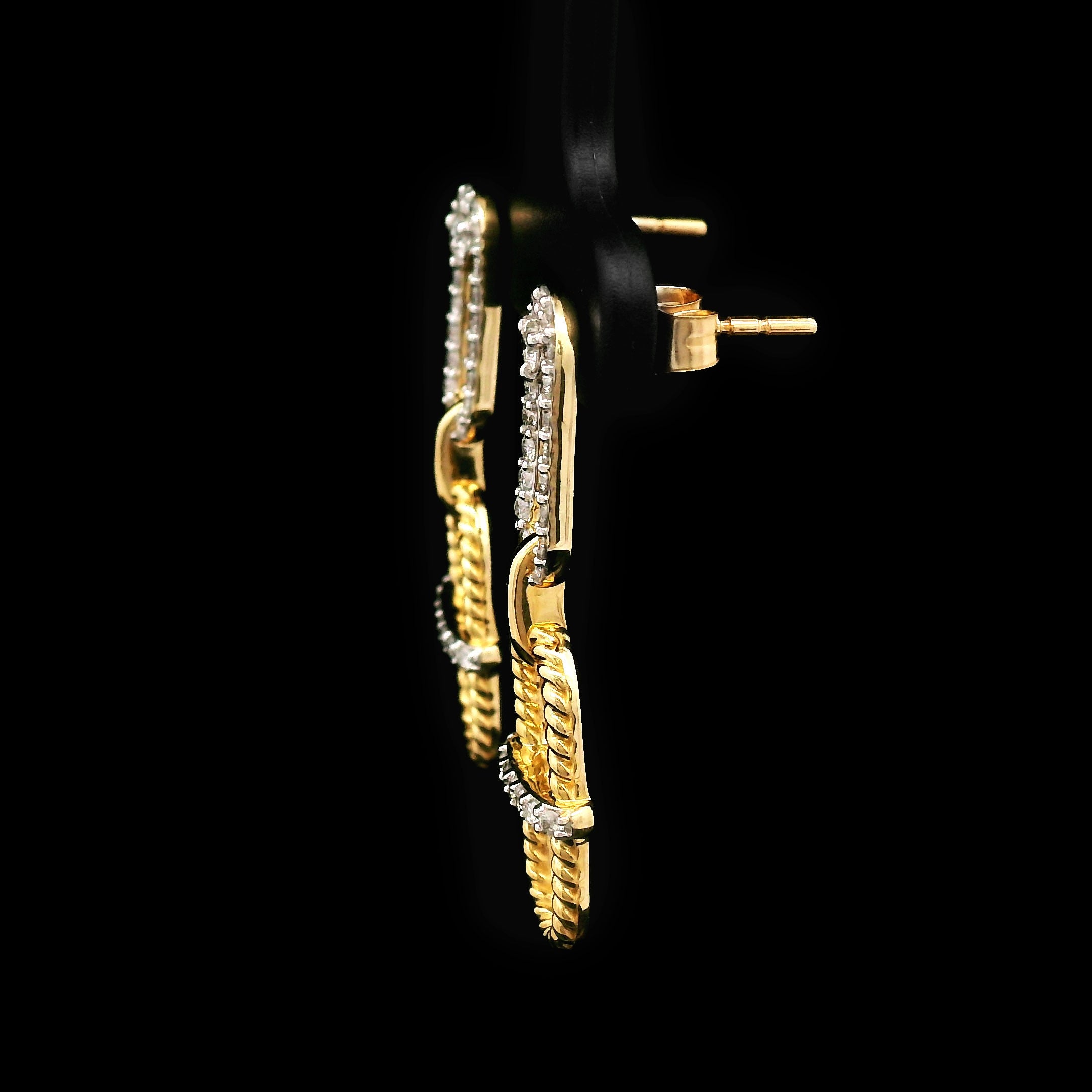 Pair of 14k gold earrings on a black background side