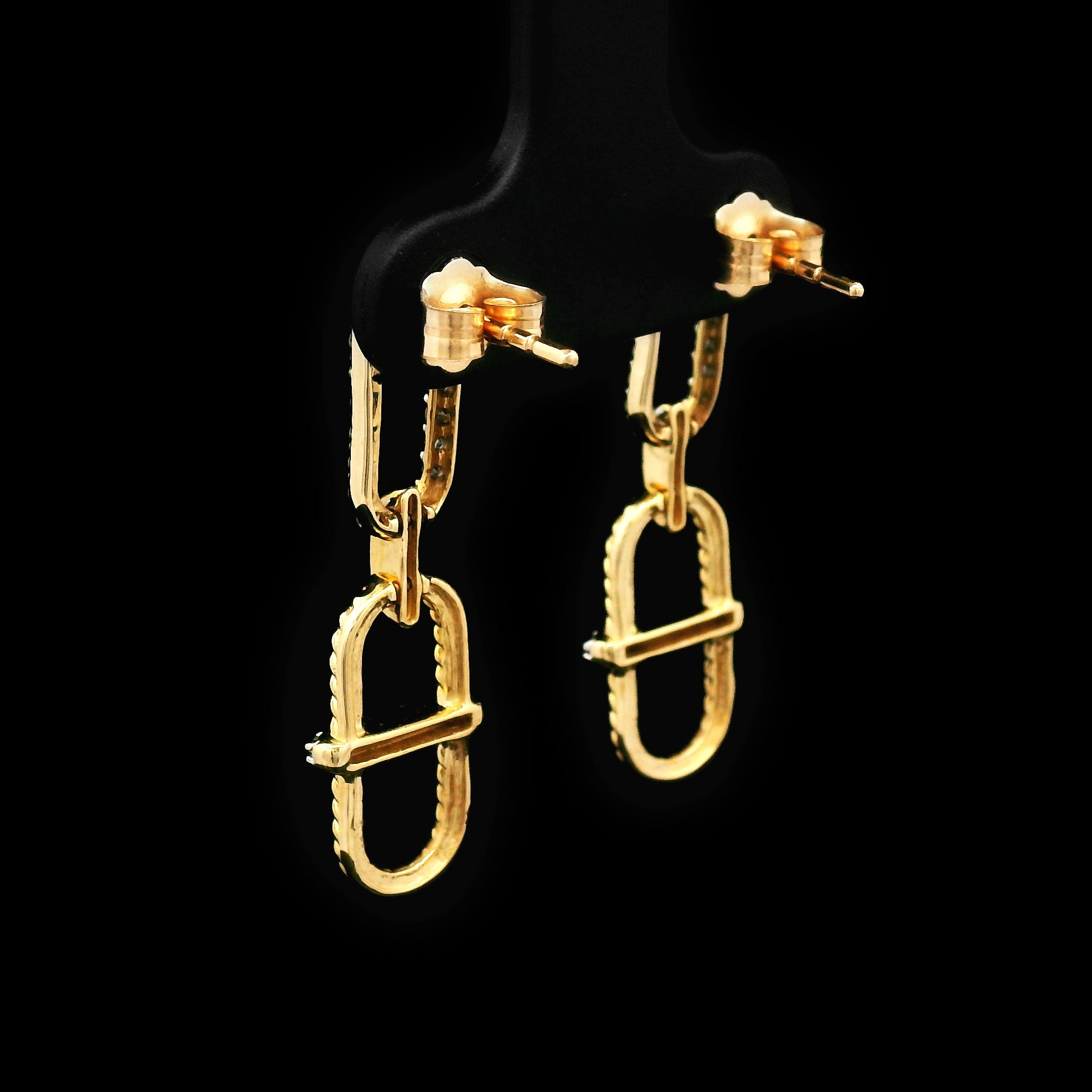 Pair of 14k gold earrings on a black background back