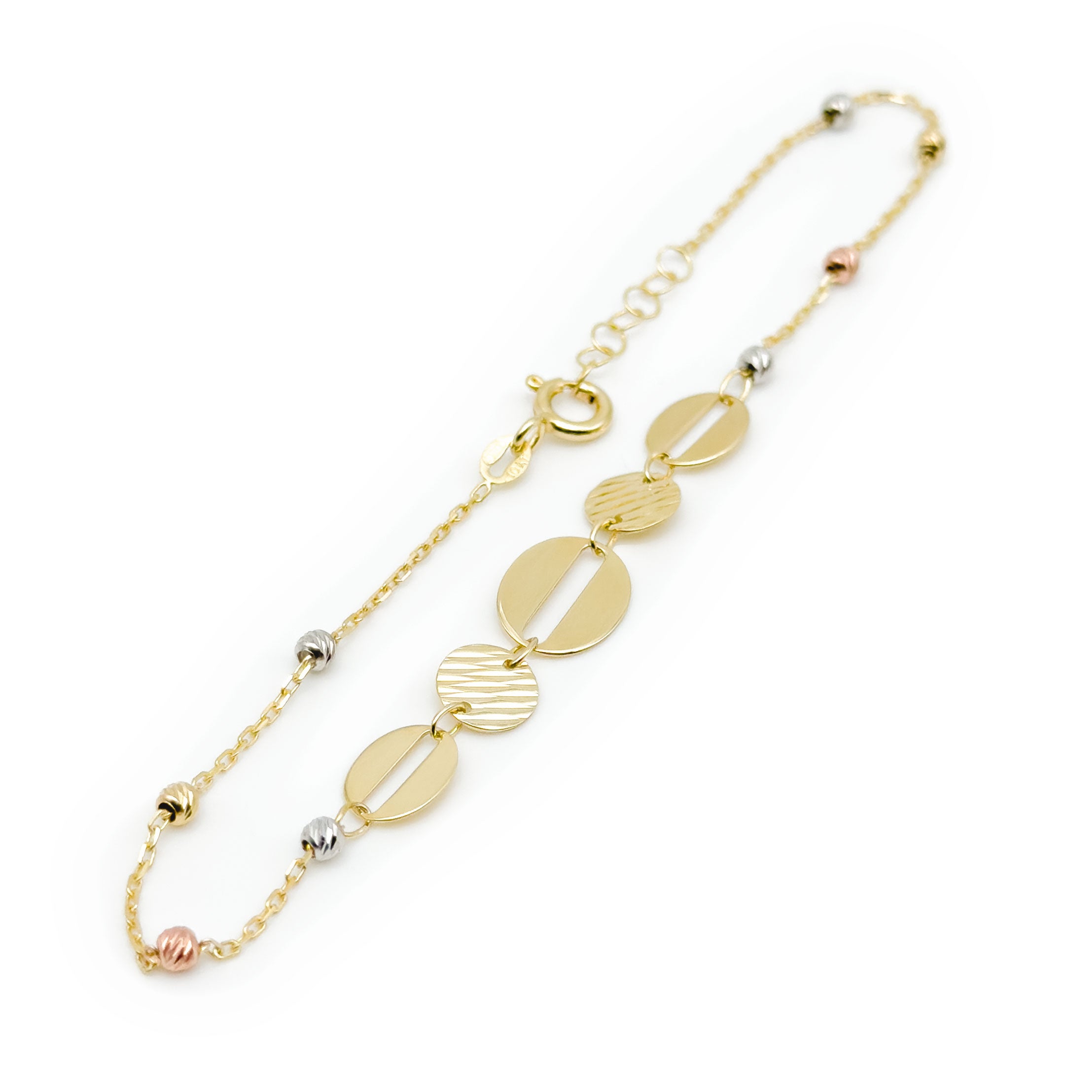 A delicate gold chain bracelet with five oval and disc charms in varying textures and sizes, accented by small white and rose gold beads, on a white background. close