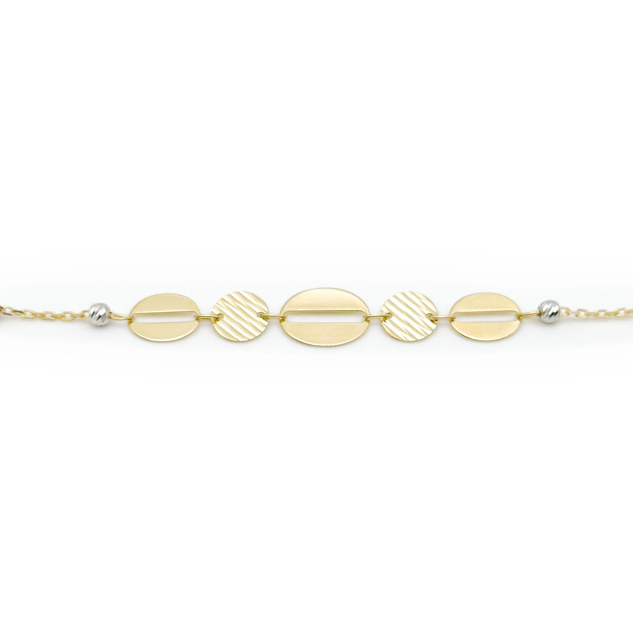 A delicate gold chain bracelet with five oval and disc charms in varying textures and sizes, accented by small white and rose gold beads, on a white background. close up of charms
