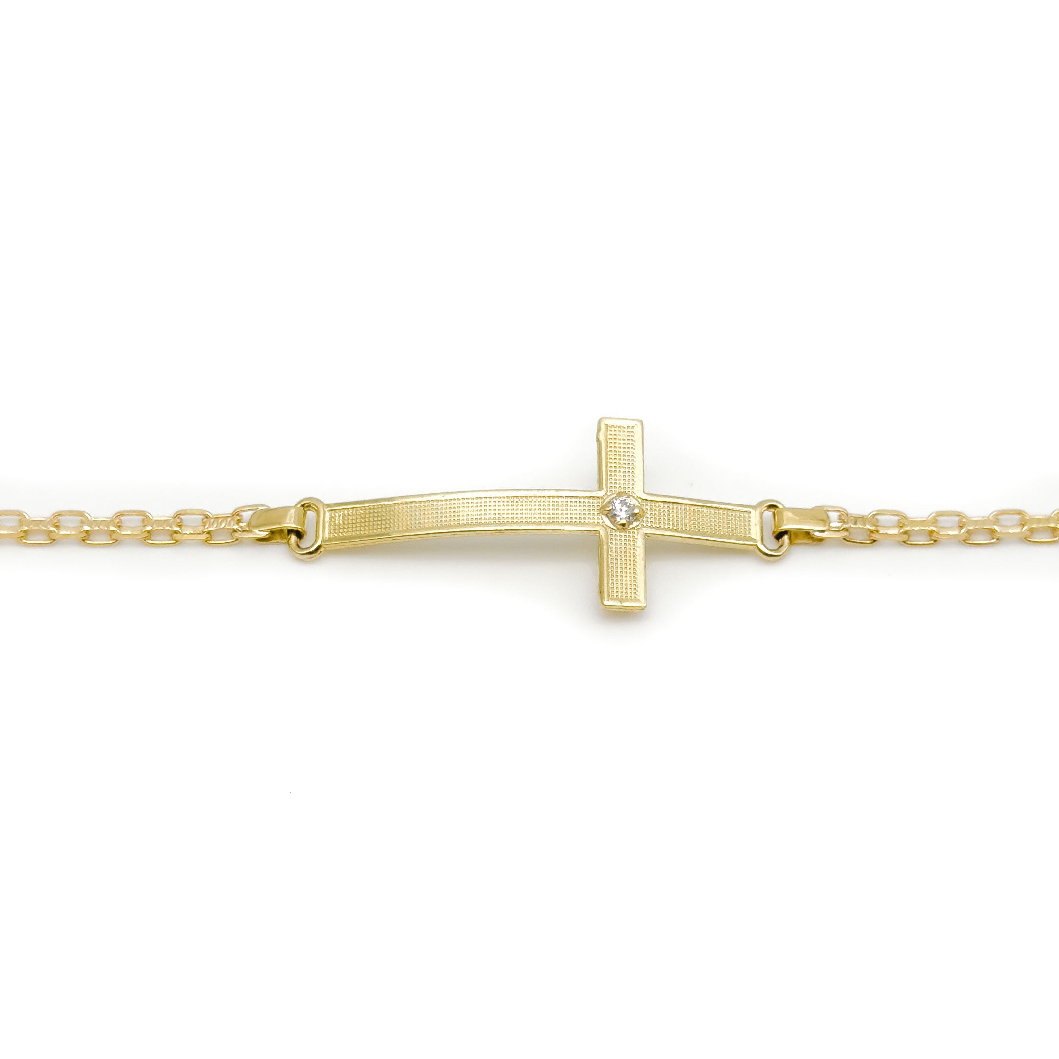 A gold chain bracelet with a horizontal cross pendant featuring a small cz stone at the center, photographed on a plain white background. close up of charm