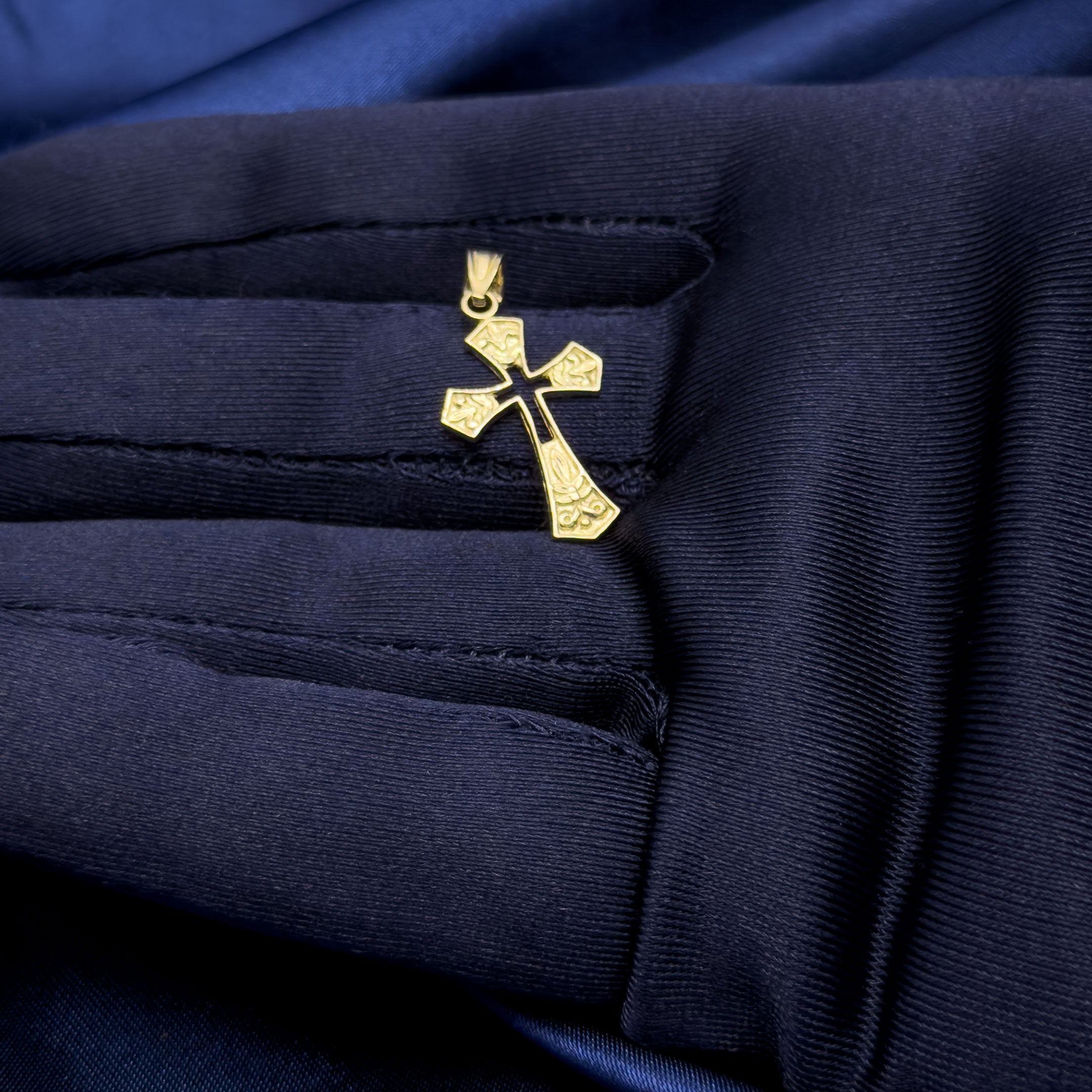 10k yellow gold Victorian shaped cross with filigree details and cut-out in center pendant in hand with blue glove