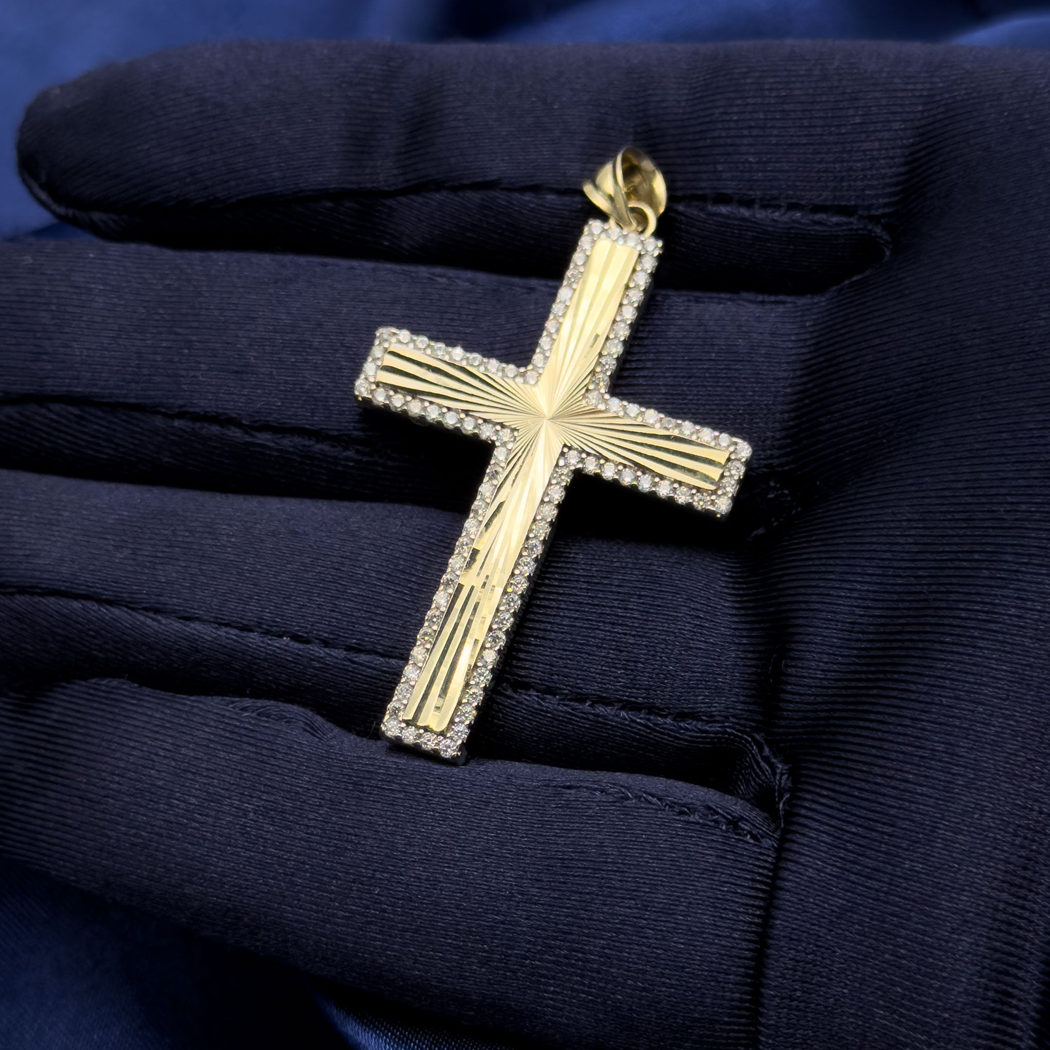 10k yellow gold diamond cut cross with cubic zirconia border pendant in a hand with navy blue glove