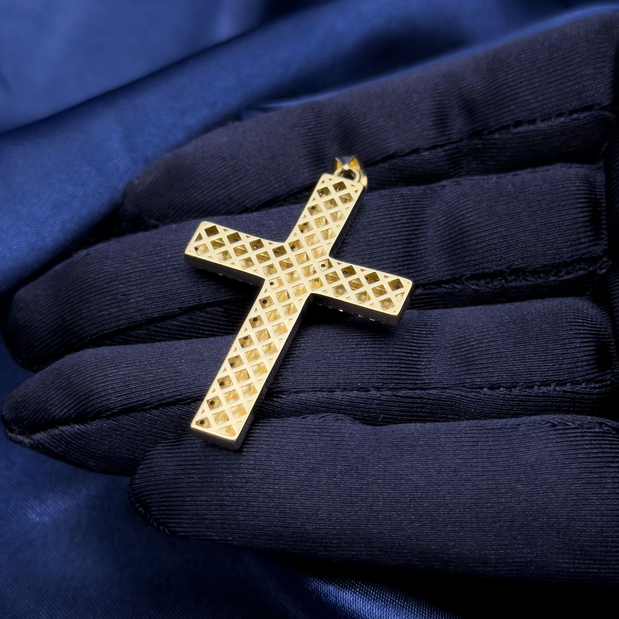10k yellow gold diamond cut cross with cubic zirconia border pendant in a hand with navy blue glove back