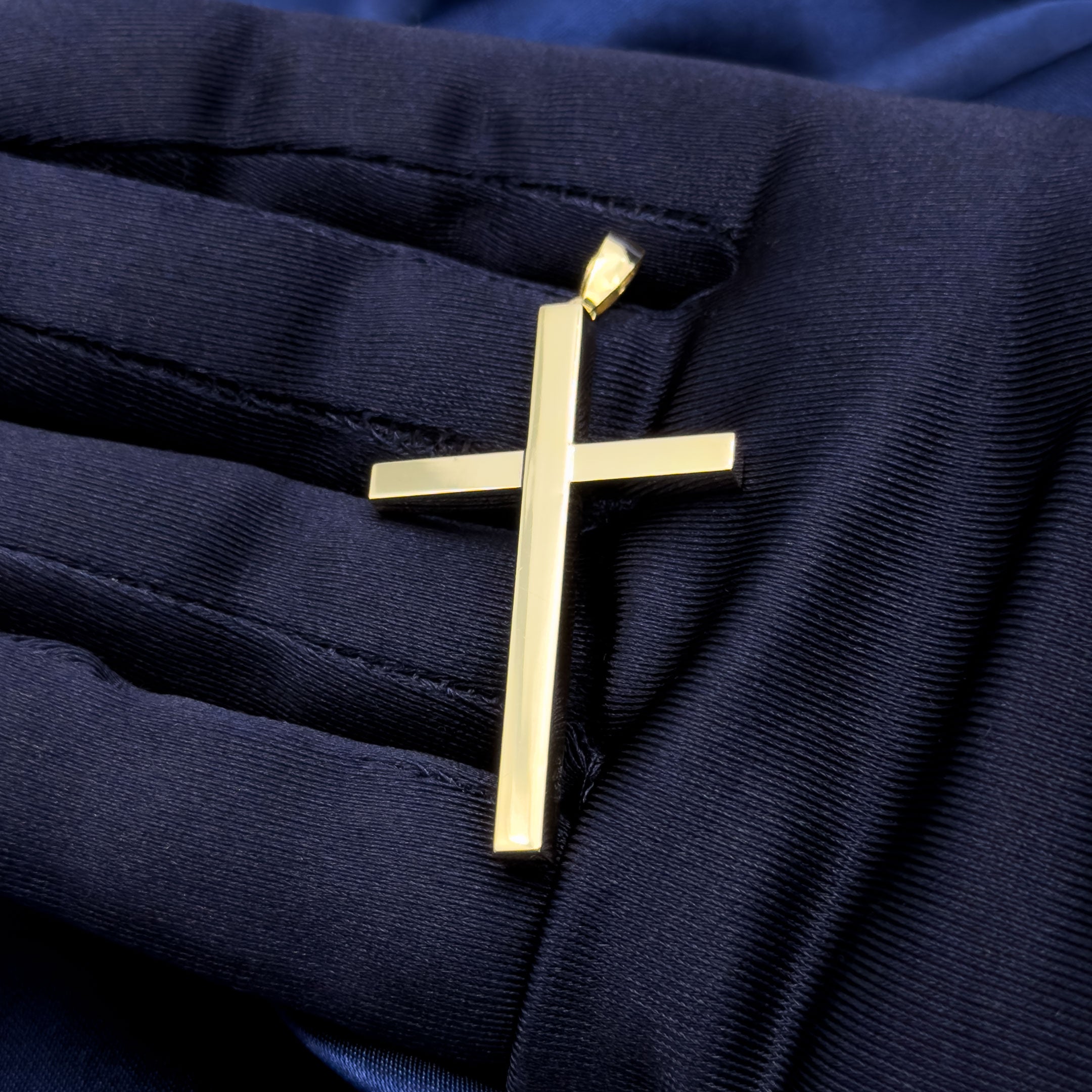10k yellow gold square design cross pendant in hand with blue glove