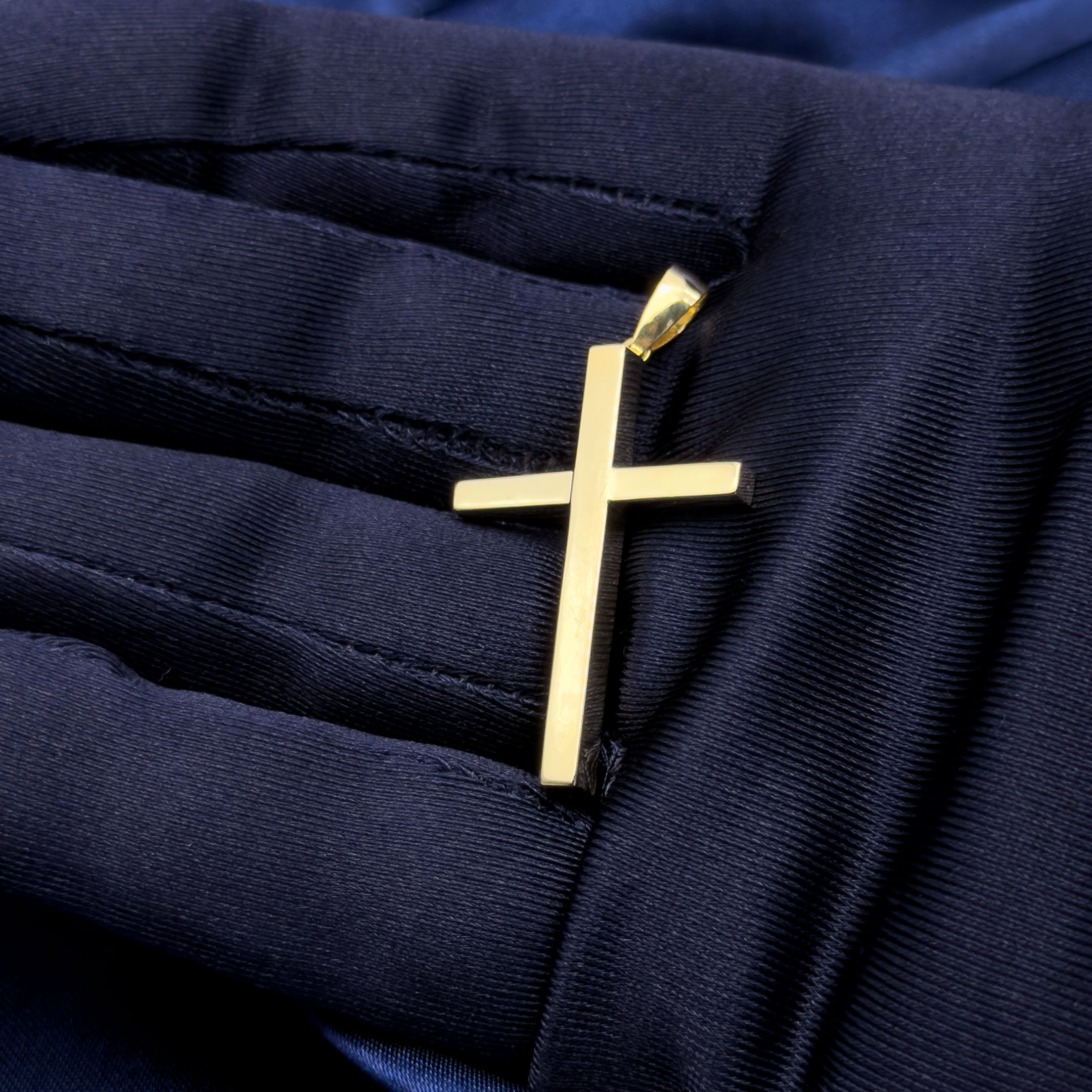 10k yellow gold square shaped cross pendant in hand with blue glove