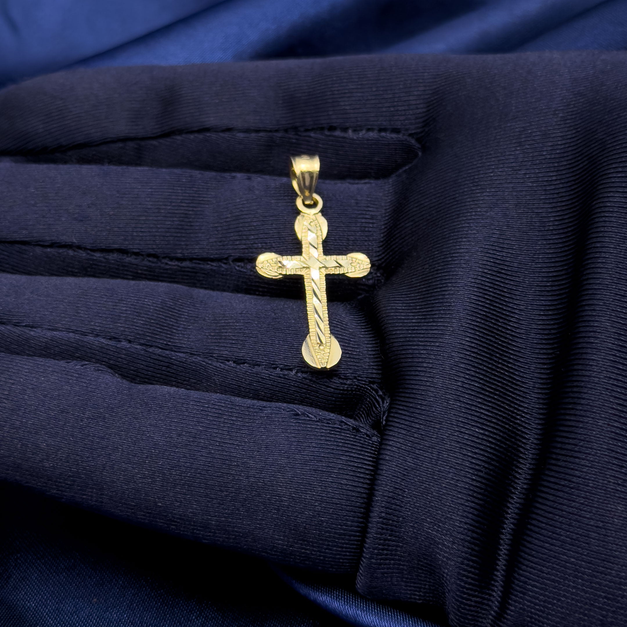 10k yellow gold diamond cut design cross pendant with round ends in hand with blue glove