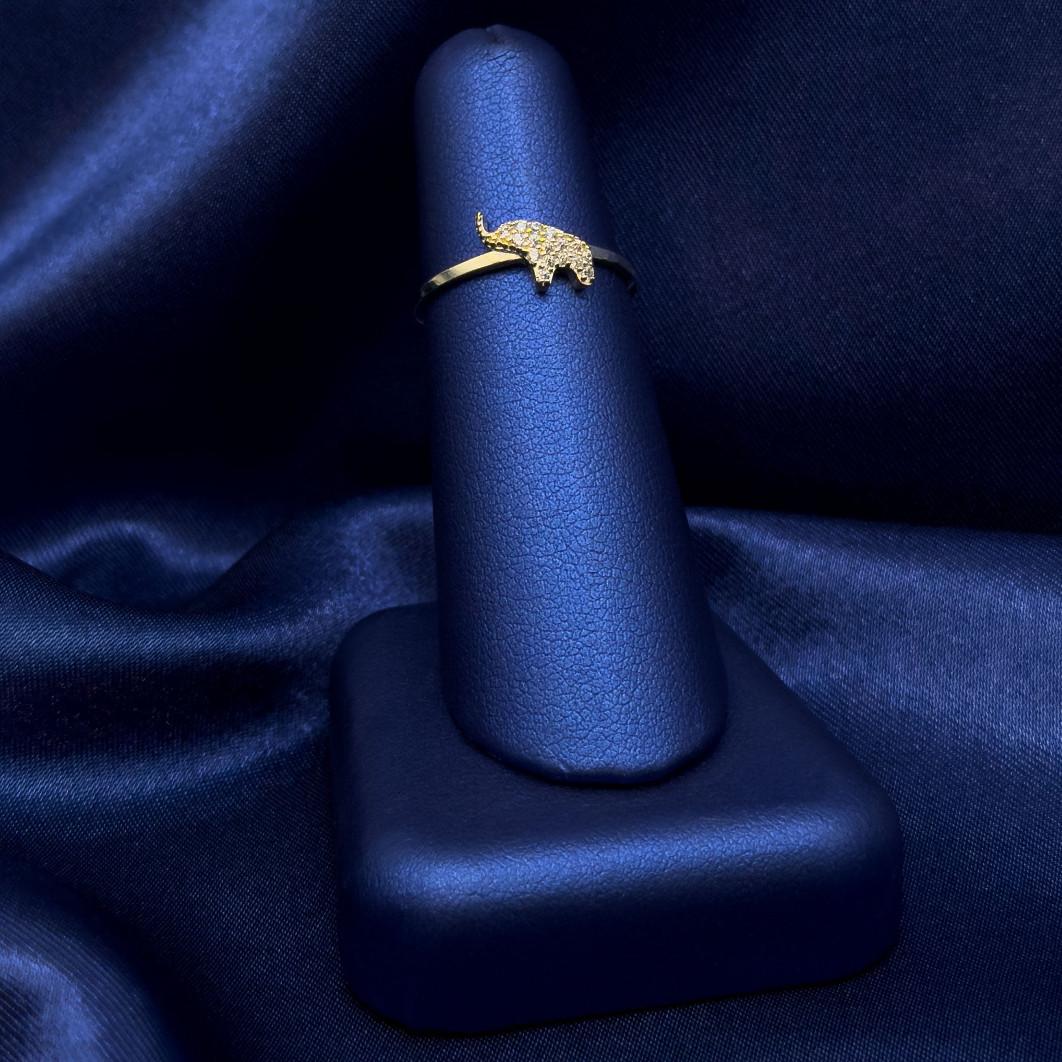 10k Gold CZ Elephant Dainty Ring with trunk facing up on a blue satin background
