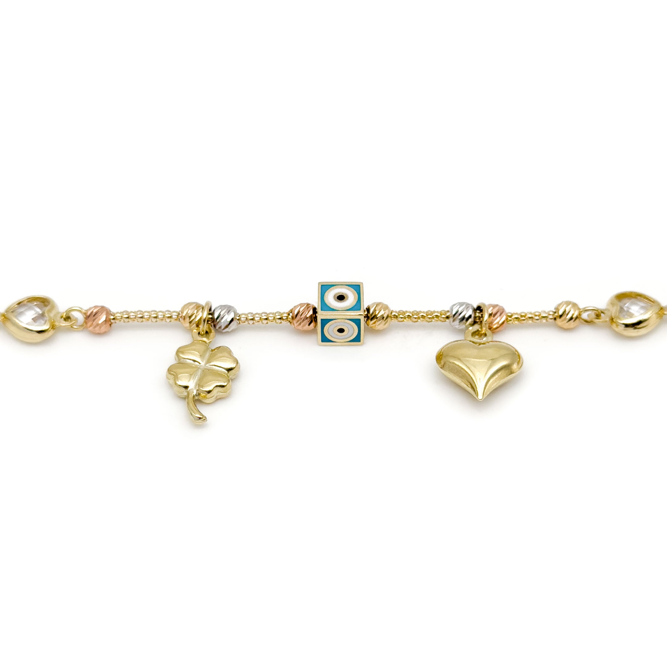 A gold cable chain bracelet with a clasp, featuring heart-shaped bezel-set clear stones, a central evil eye square charm, a dangling gold four-leaf clover charm, and a dangling gold heart charm, all displayed on a clean white background. close up of charms