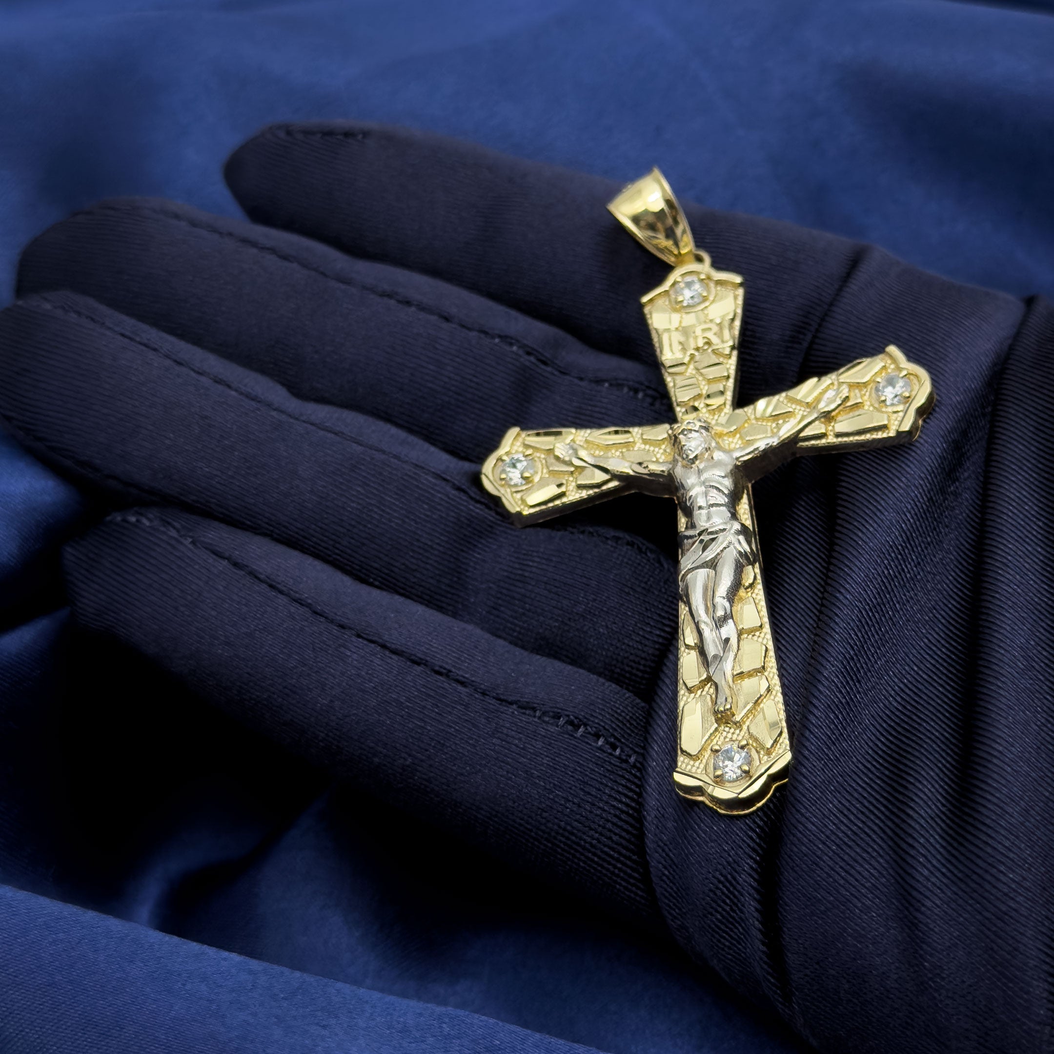 10k Yellow Gold Nugget Crucifix Flare Cross Pendant with blue background in hand