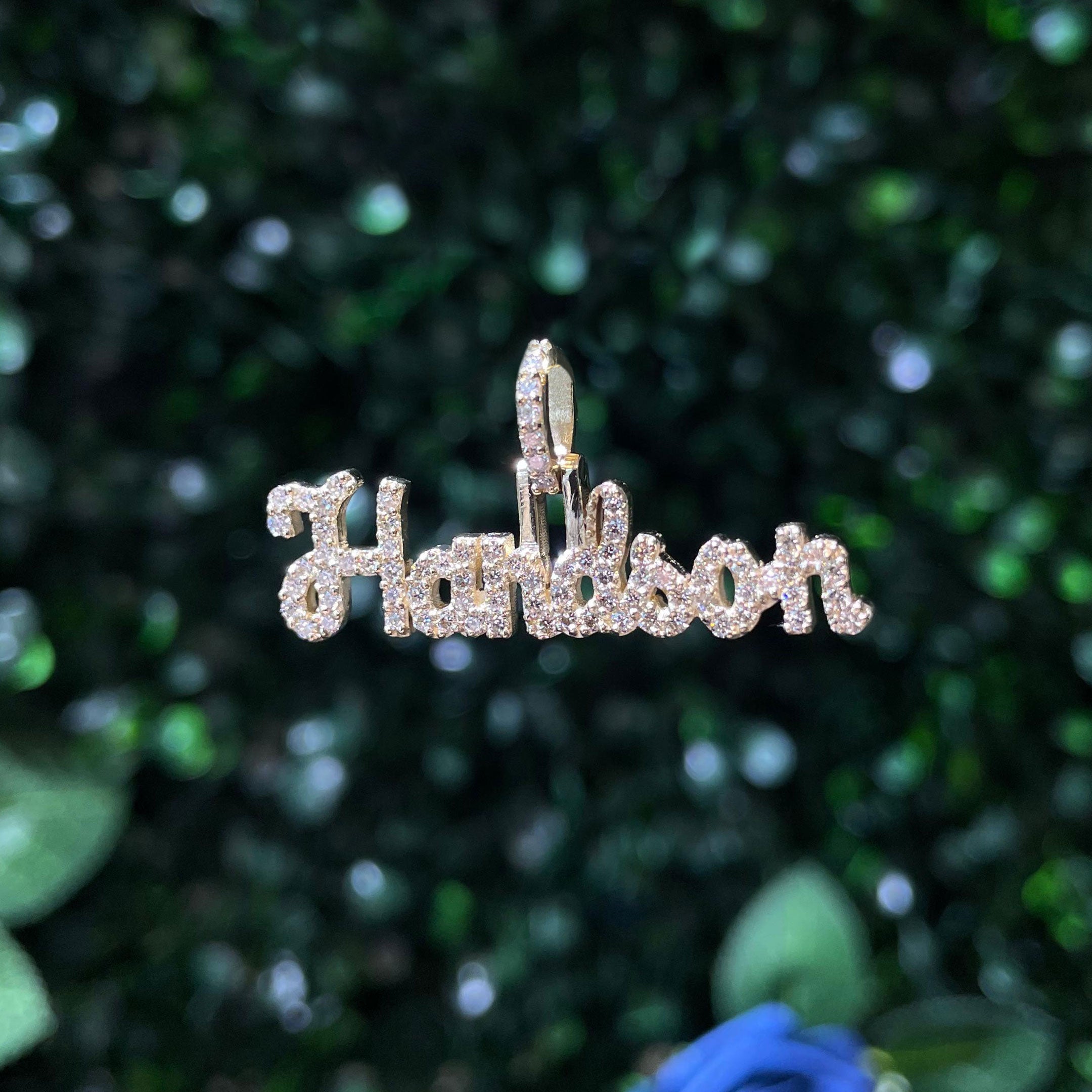 Gold name "Handson" pendant with diamonds on a green leafy background