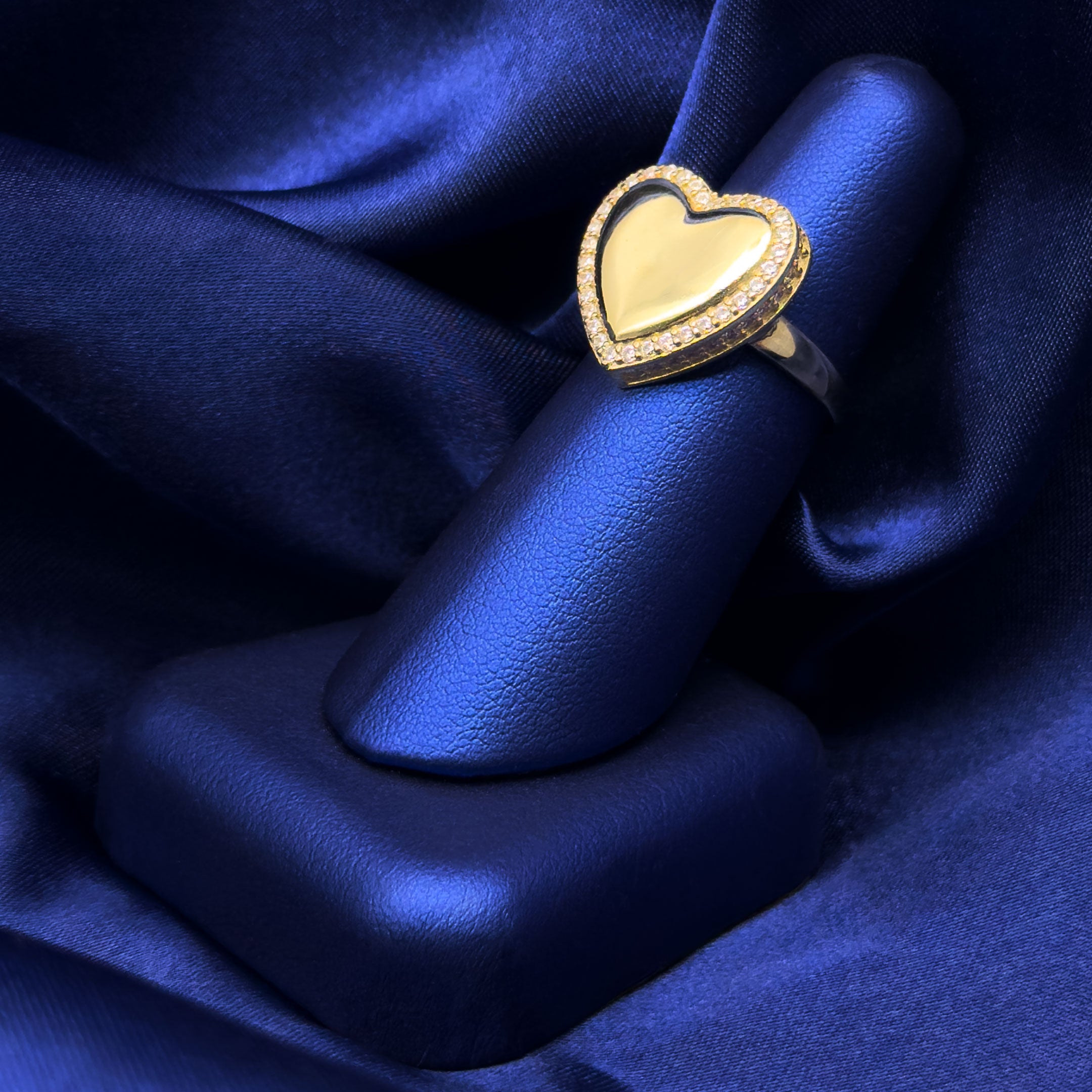 10k yellow gold heart ring with stones around border on a blue background on blue finger display