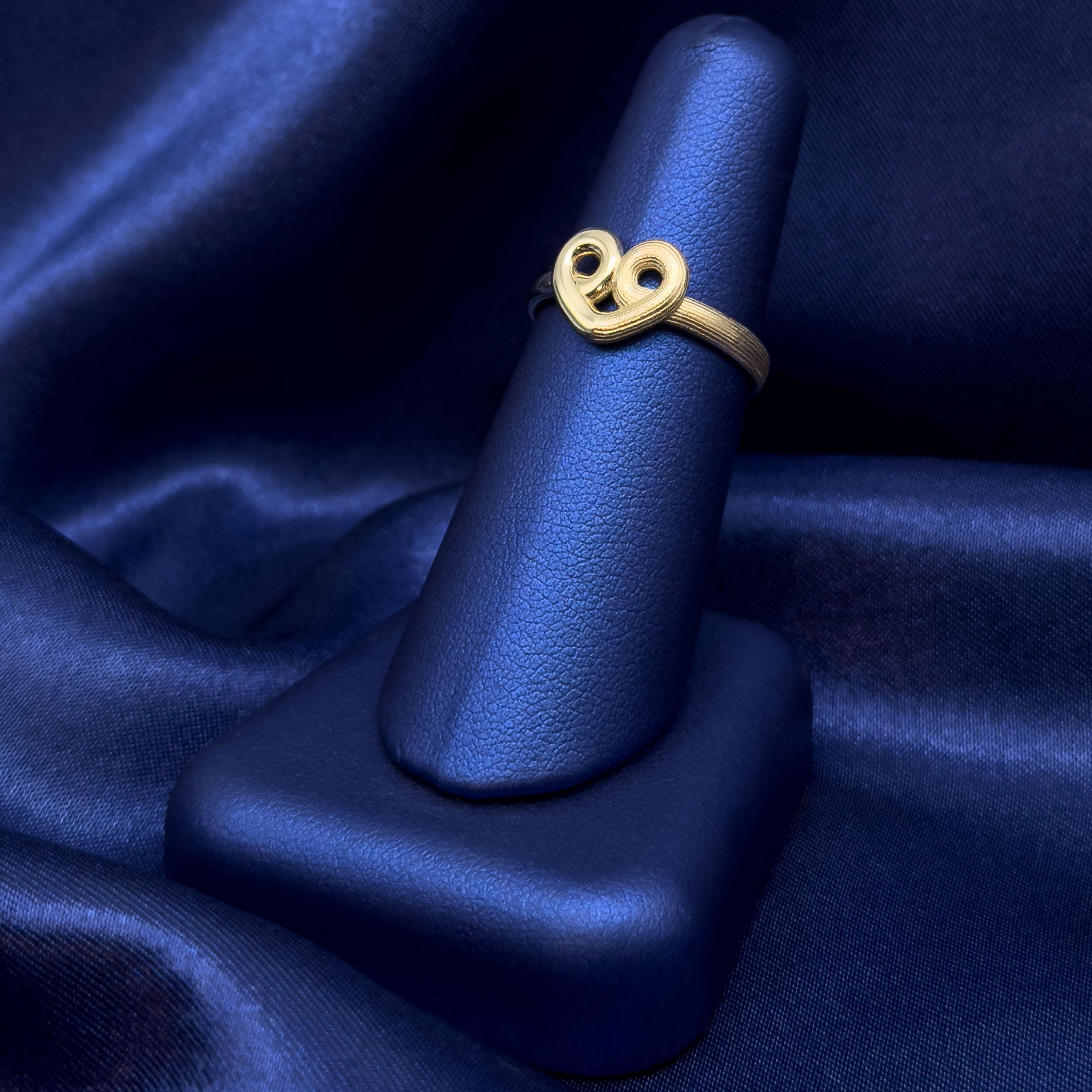 10k Gold Heart Swirl Ring with Half High Polish and Half Satin Finish on a Blue Background