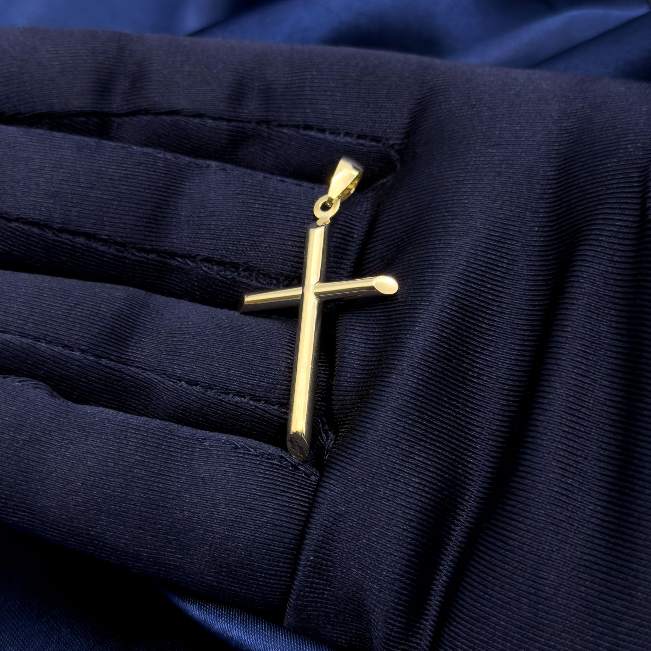 10k yellow gold high polished cross pendant in hand with blue glove