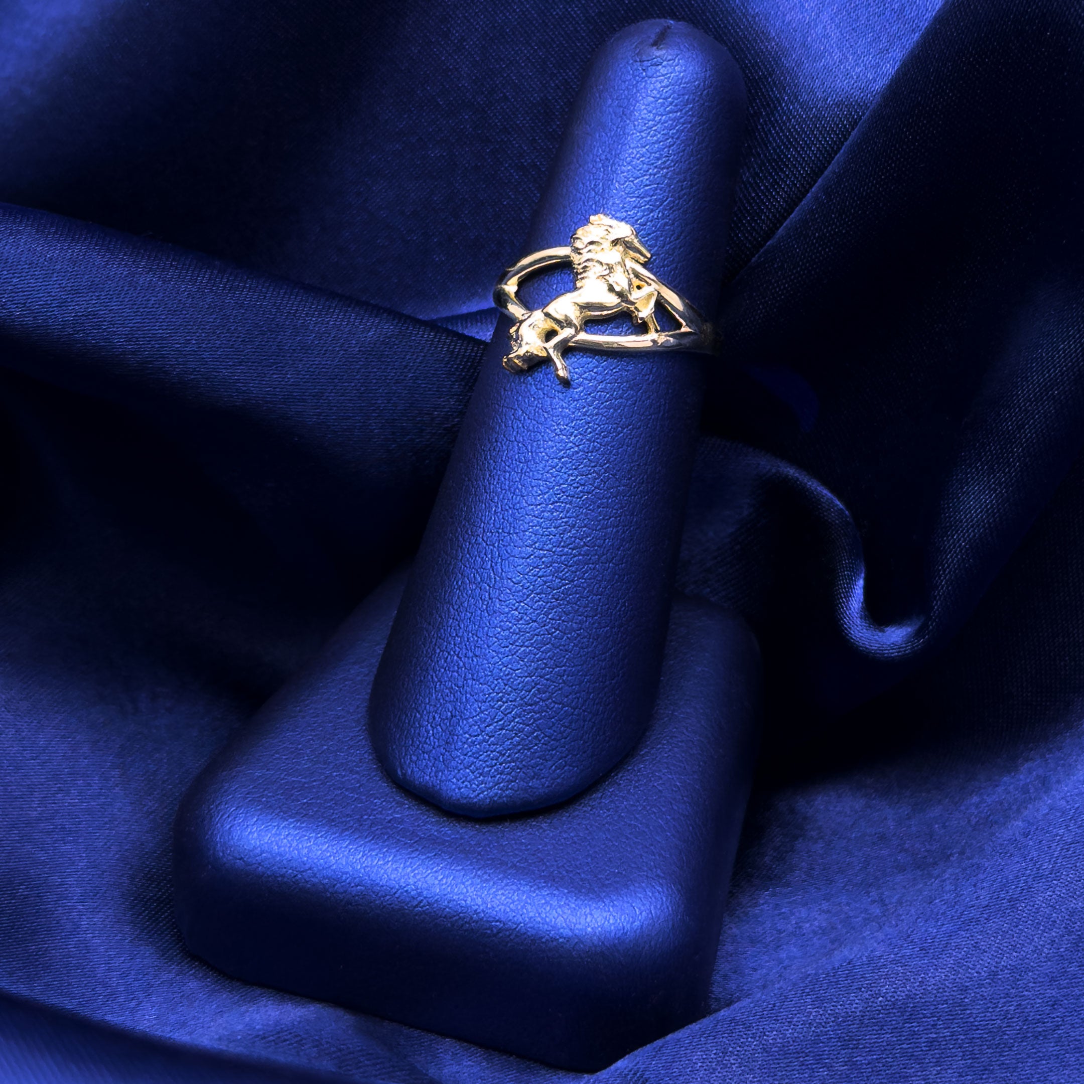10k yellow gold ring with a horse in rearing pose on a blue finger display