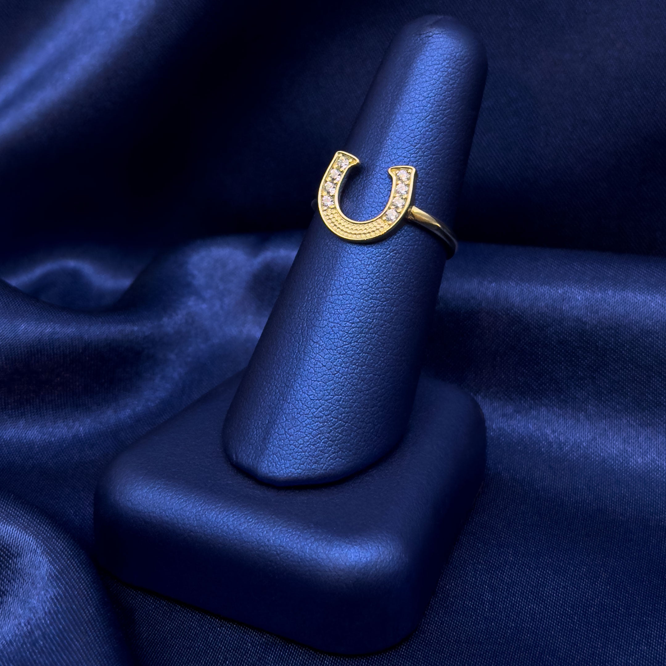10k CZ Horseshoe Ring Facing Up on a blue satin background