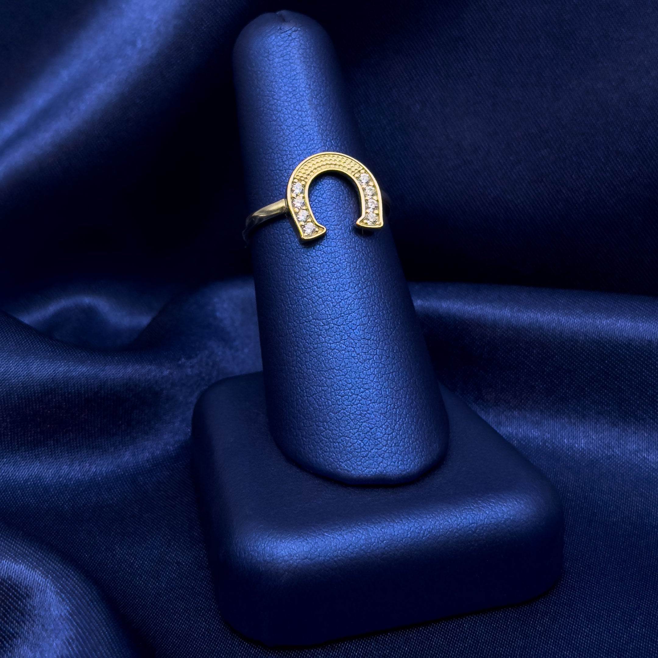 10k CZ Horseshoe Ring Facing Down on a blue satin background