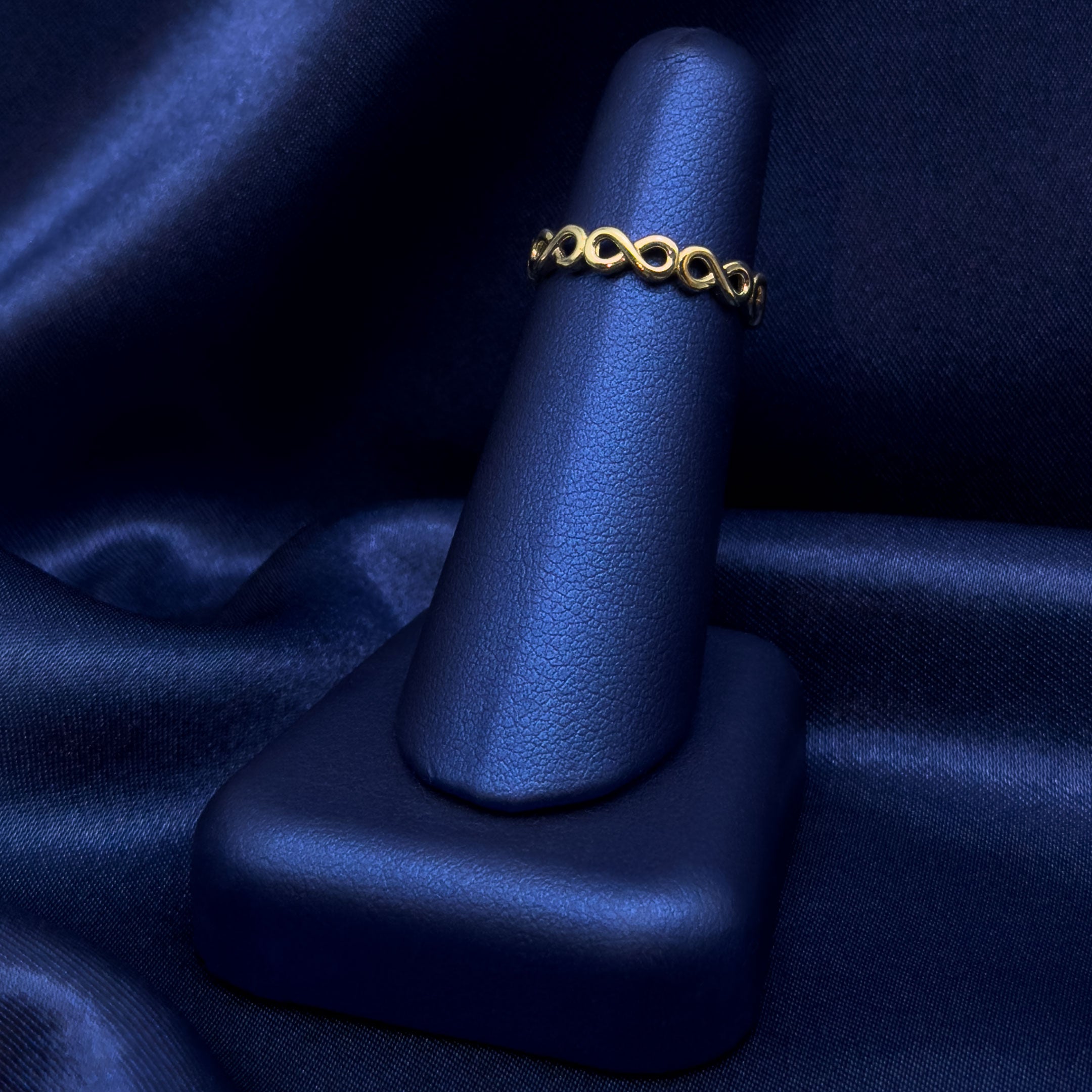 10k Infinity Band Ring on a blue satin surface