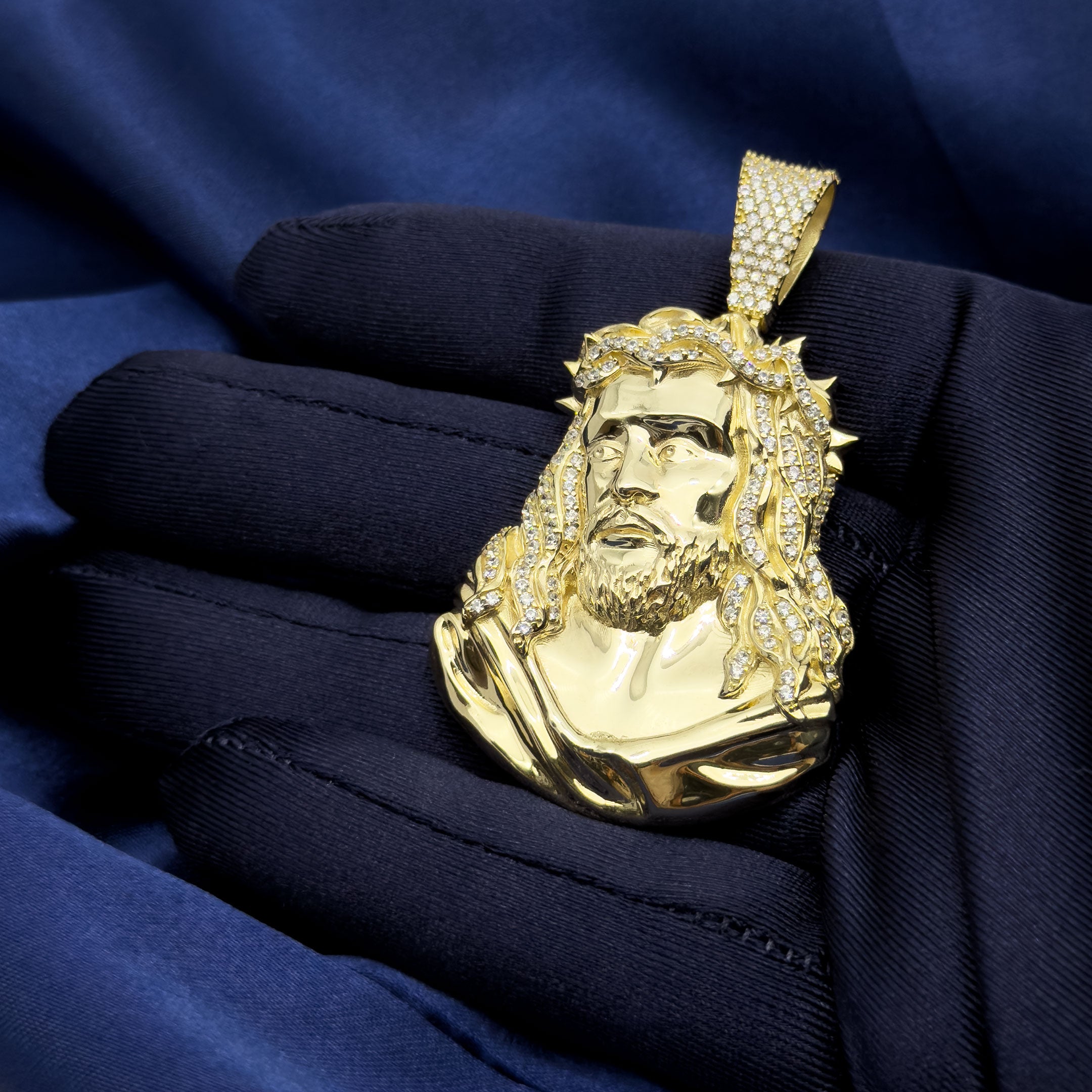 10k Yellow Gold Jesus Head Pendant with Thorns on blue background in hand