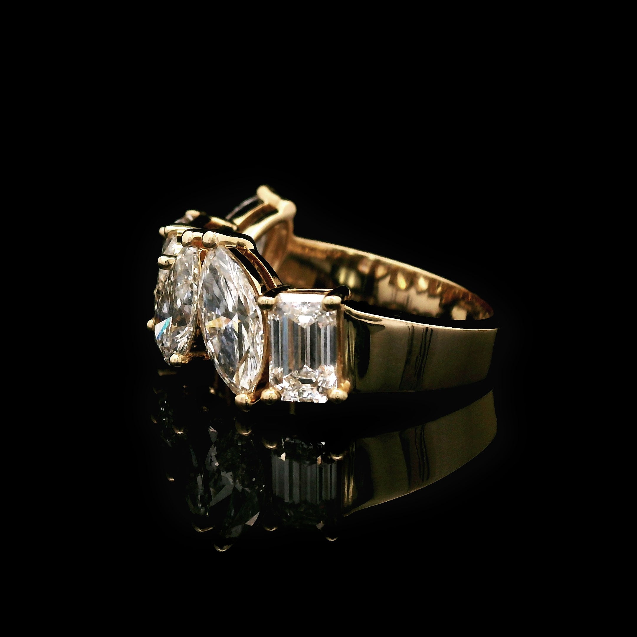 Gold wedding band with marquise, emerald, oval and pear shaped diamonds on a black background side