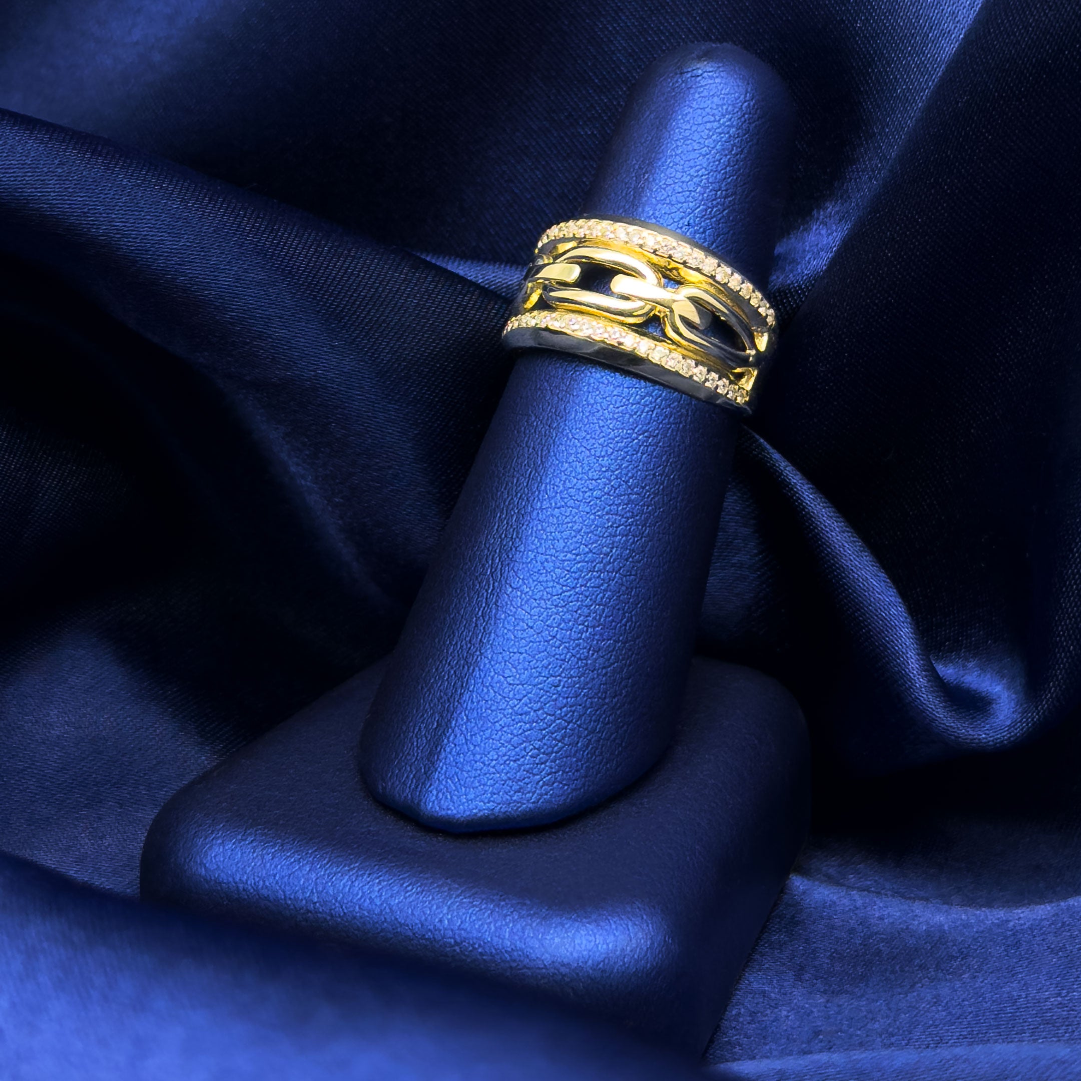 10k yellow gold with row of cz on top and bottom and link design in center on a blue finger jewelry display