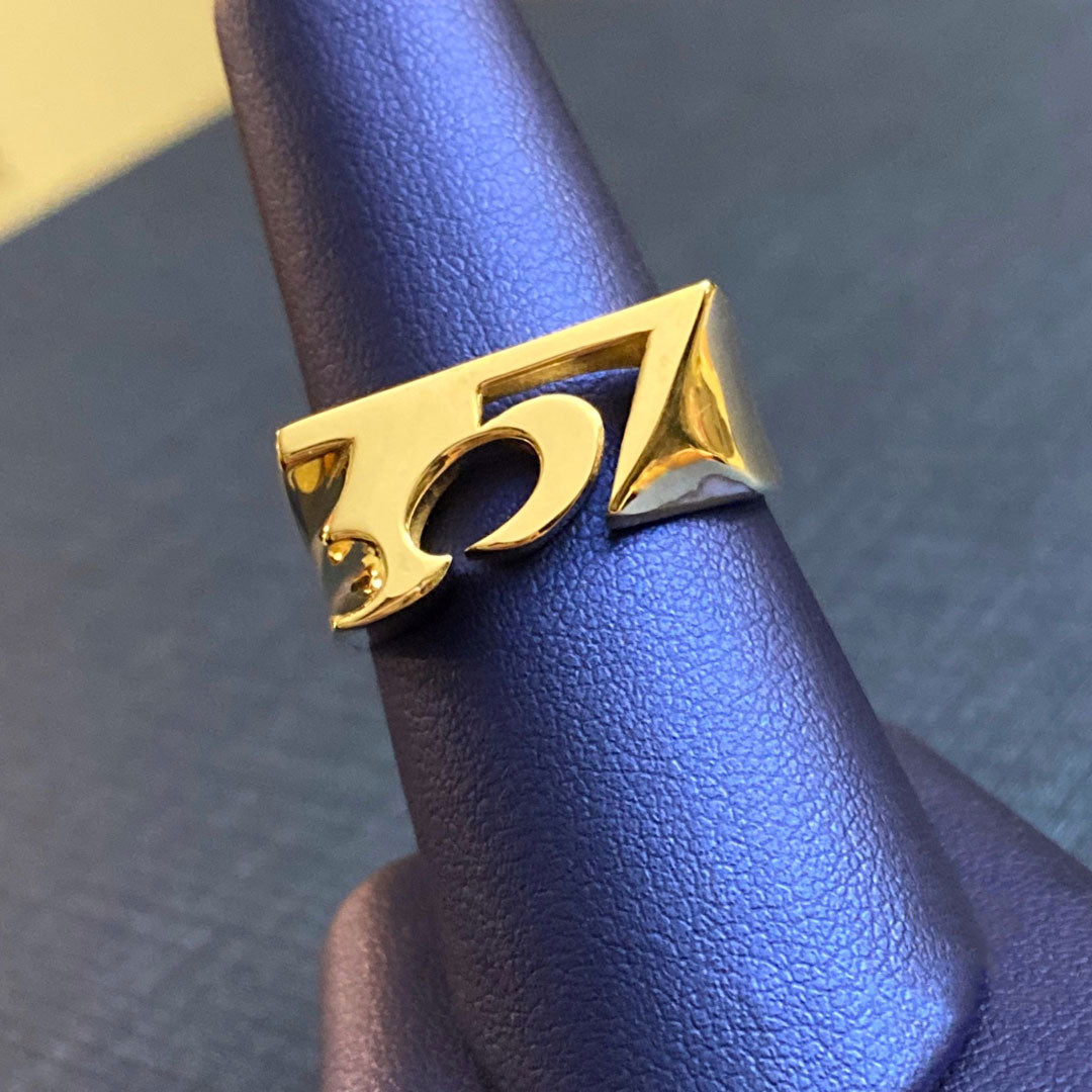 Gold ring with the number '357' on a blue textured surface