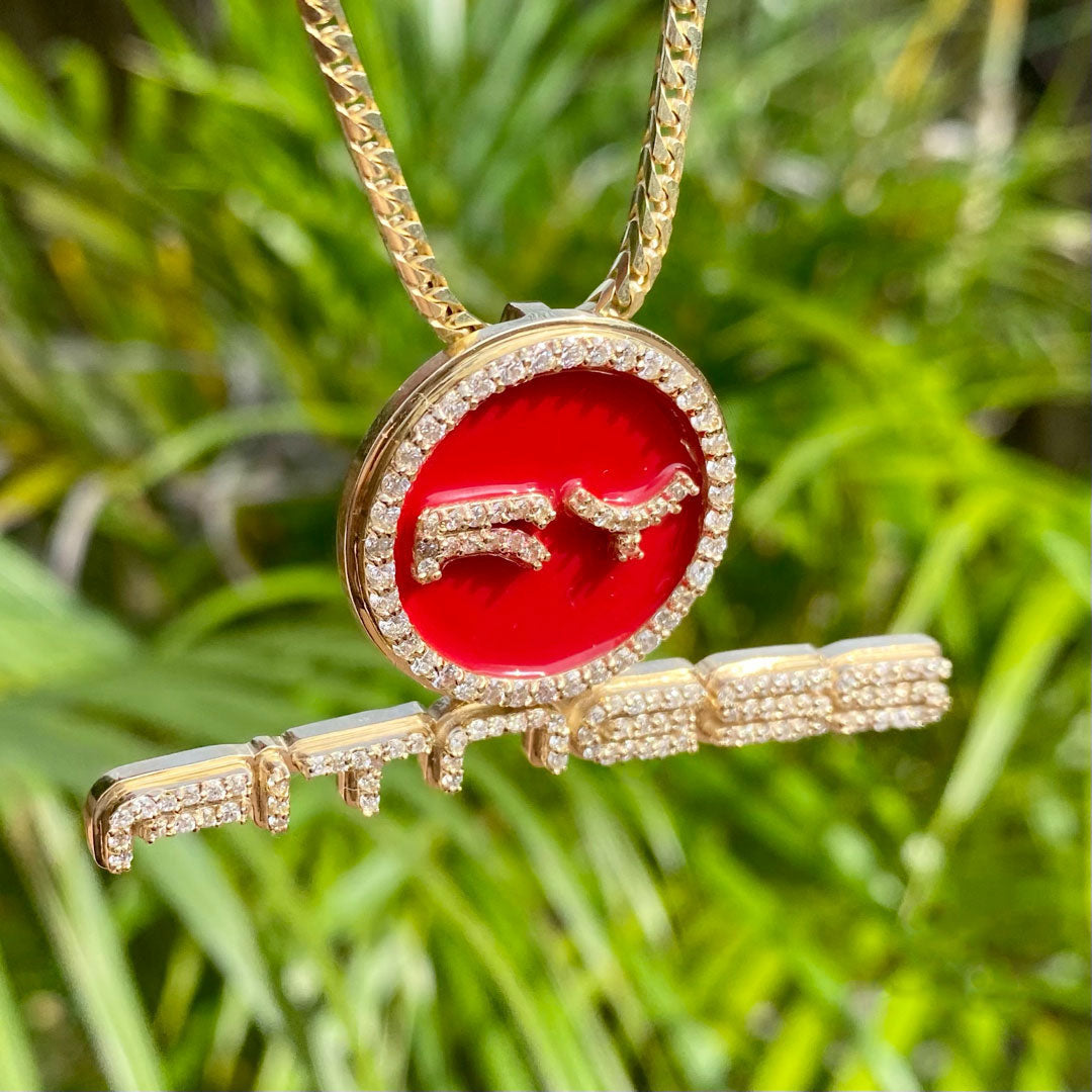 Gold necklace with a red pendant featuring a RyFitness logo against a green grass background