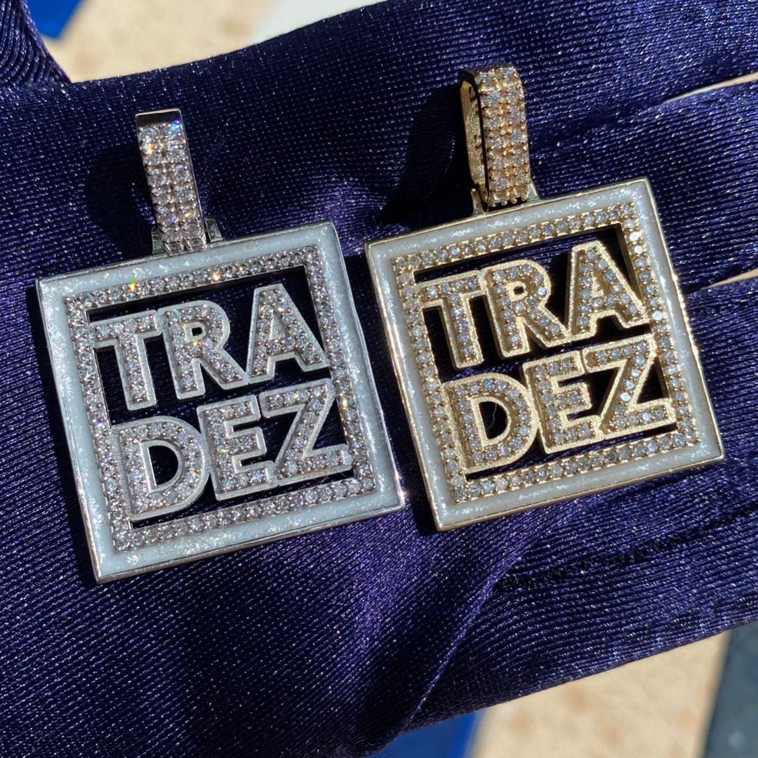 Two square pendants with 'TRA DEZ' text on a blue fabric background