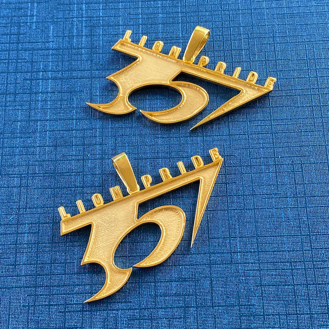 Two gold decorative items shaped like the number '357' on a blue textured background