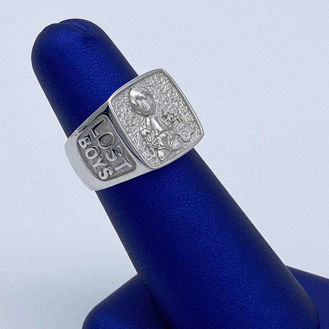 Silver ring with 'Lost Boys' engraving on a blue stand