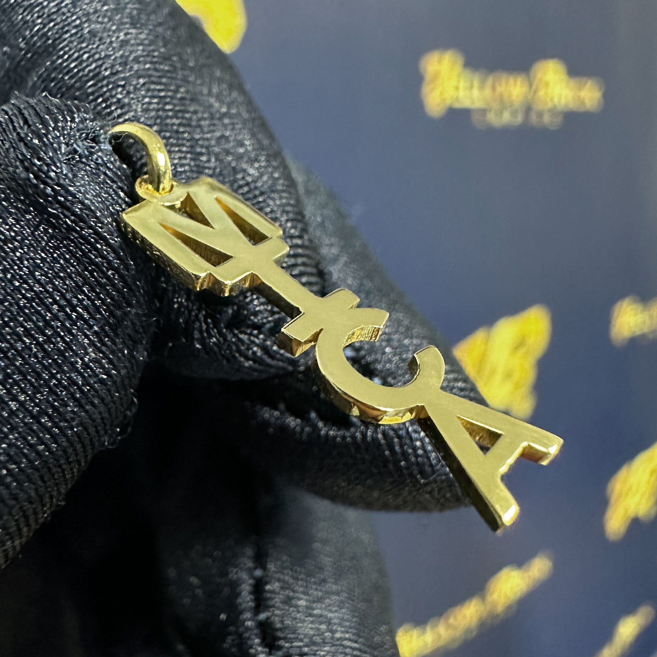 Gold pendant with 'MICA' letters close