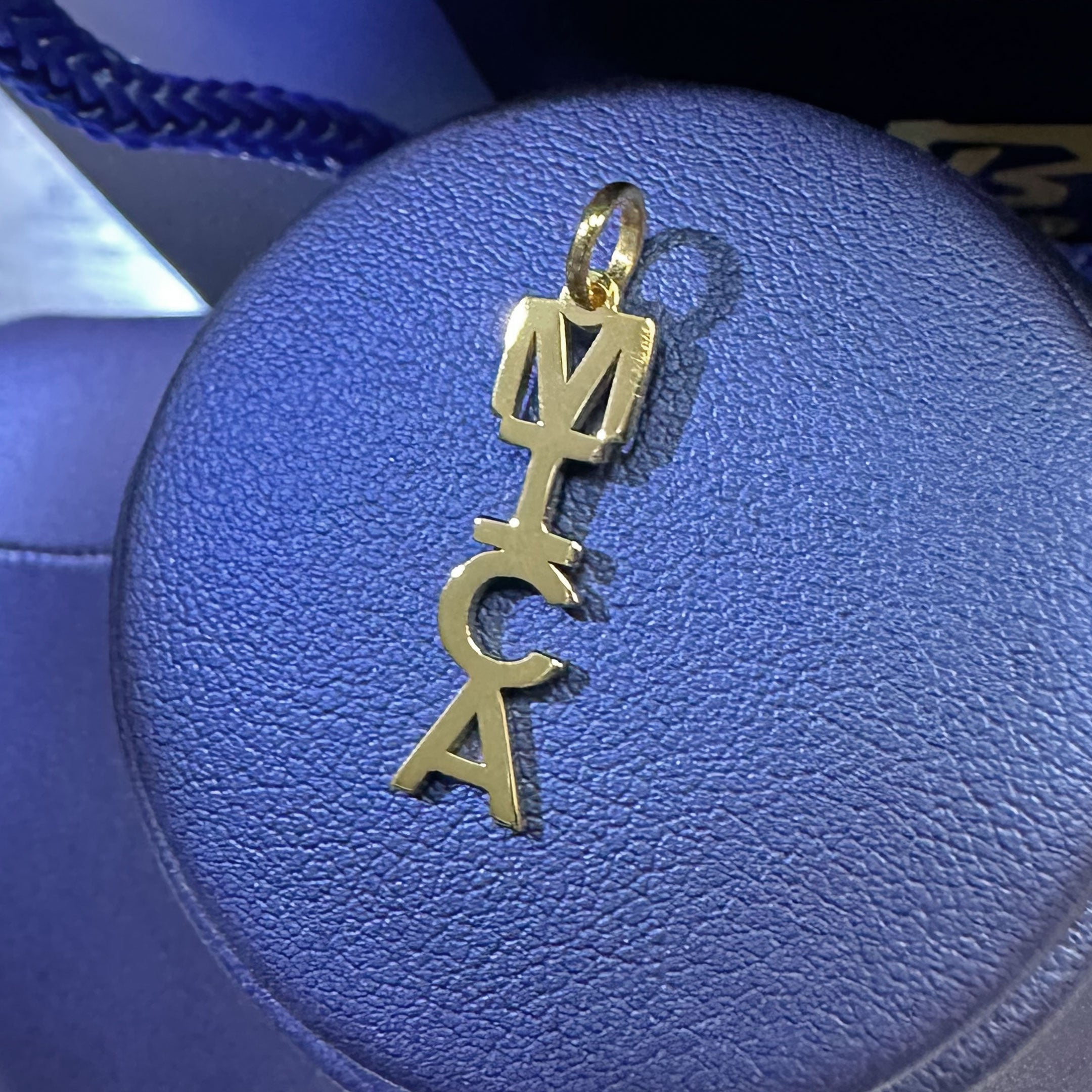 Gold pendant with 'MICA' letters