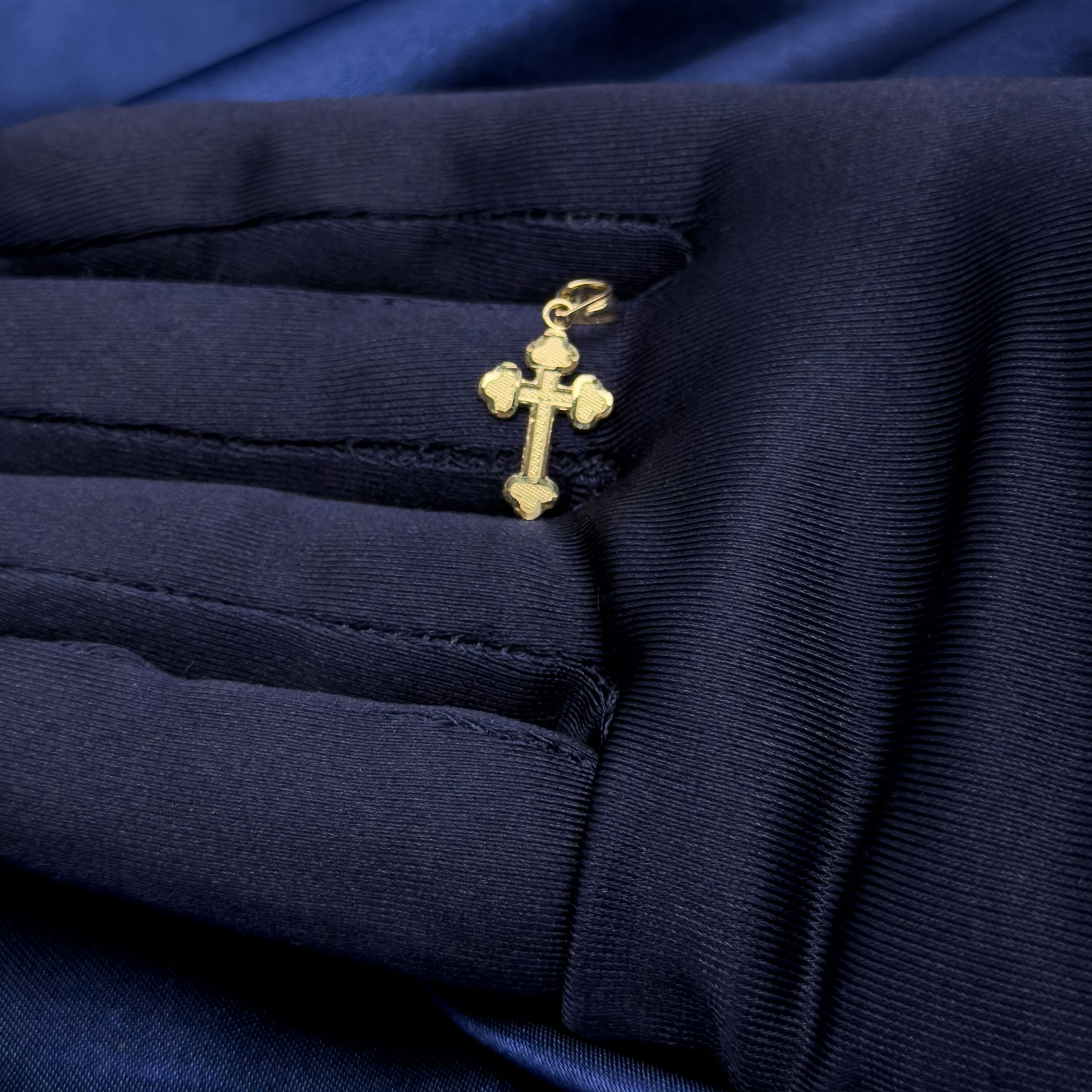 10k gold mini Trinity shaped cross pendant in hand with blue glove