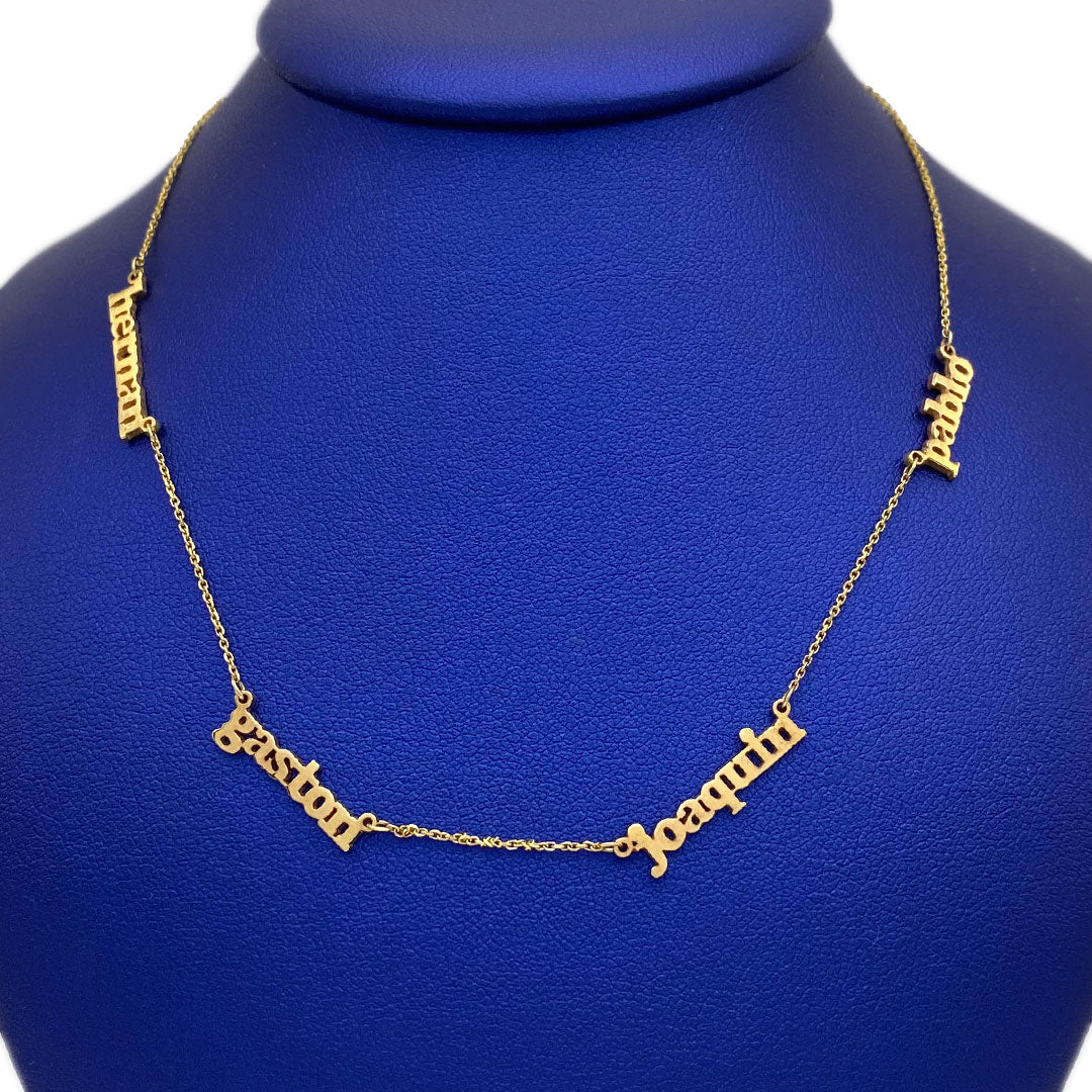 A 14k gold personalized necklace with multiple names engraved on it, displayed on a blue mannequin.