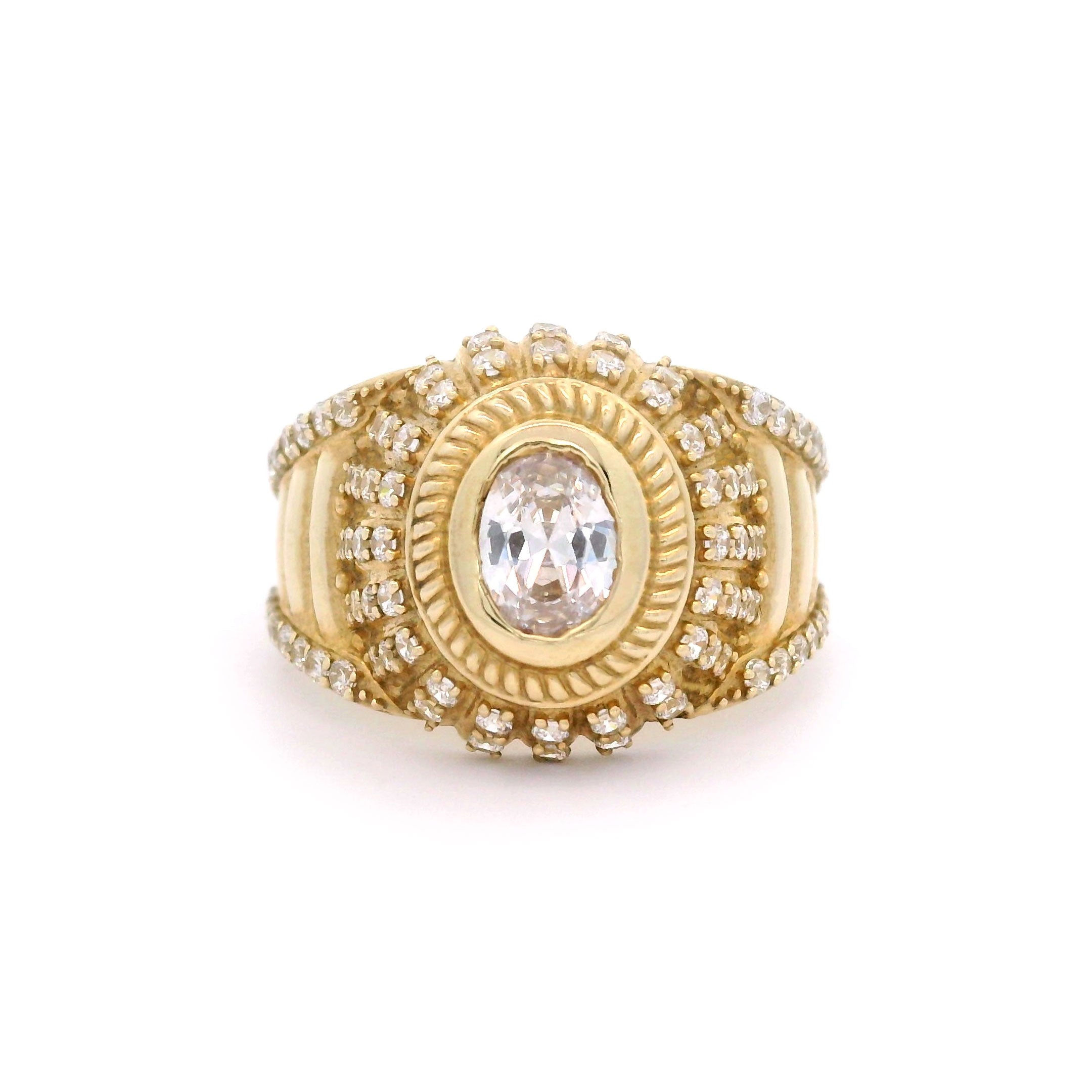 Oval gold ring with a central stone and smaller stones on a white background