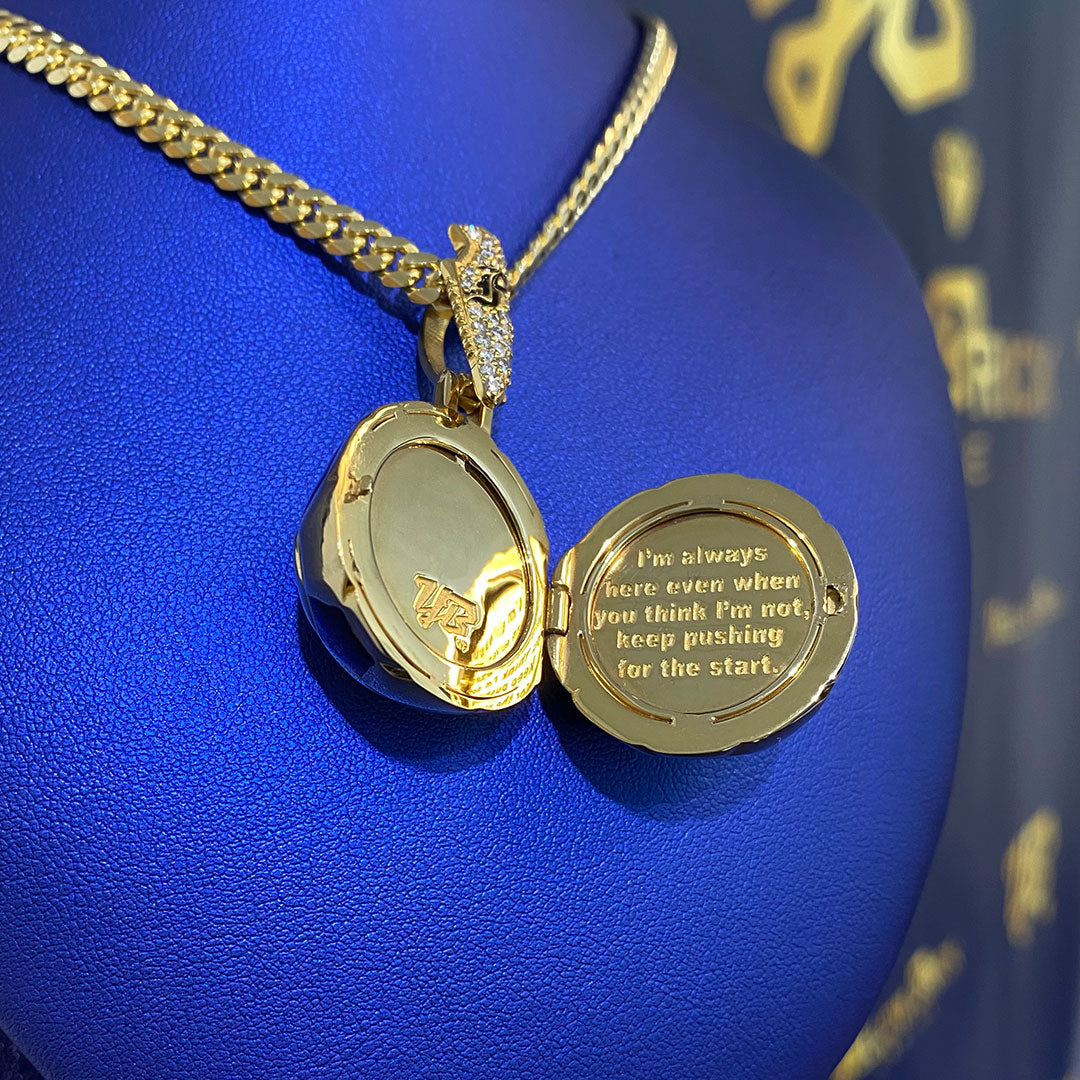 Gold soccer shaped locket with engraved message on a blue background