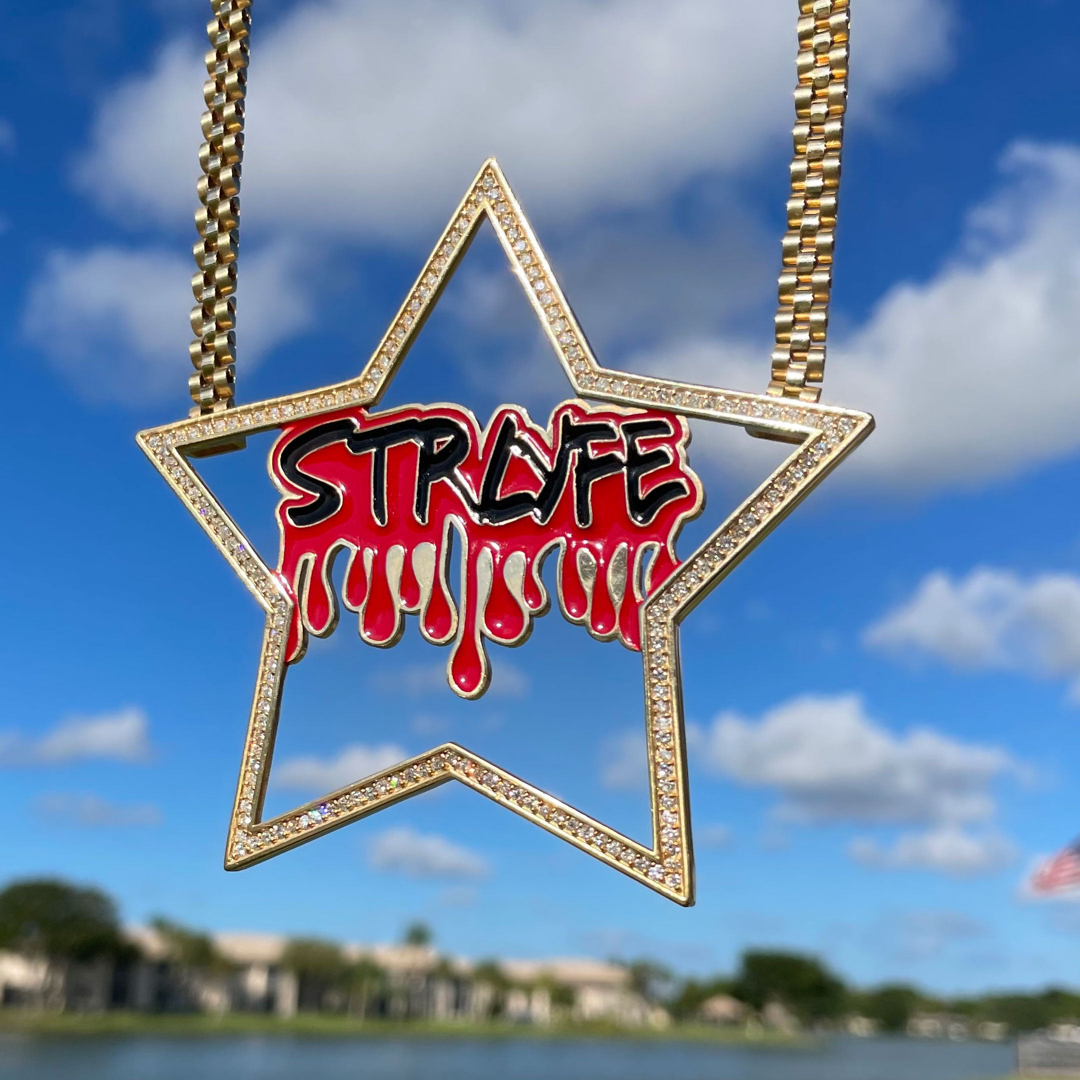 Star-shaped necklace with 'STRYFE' design against a blue sky with clouds