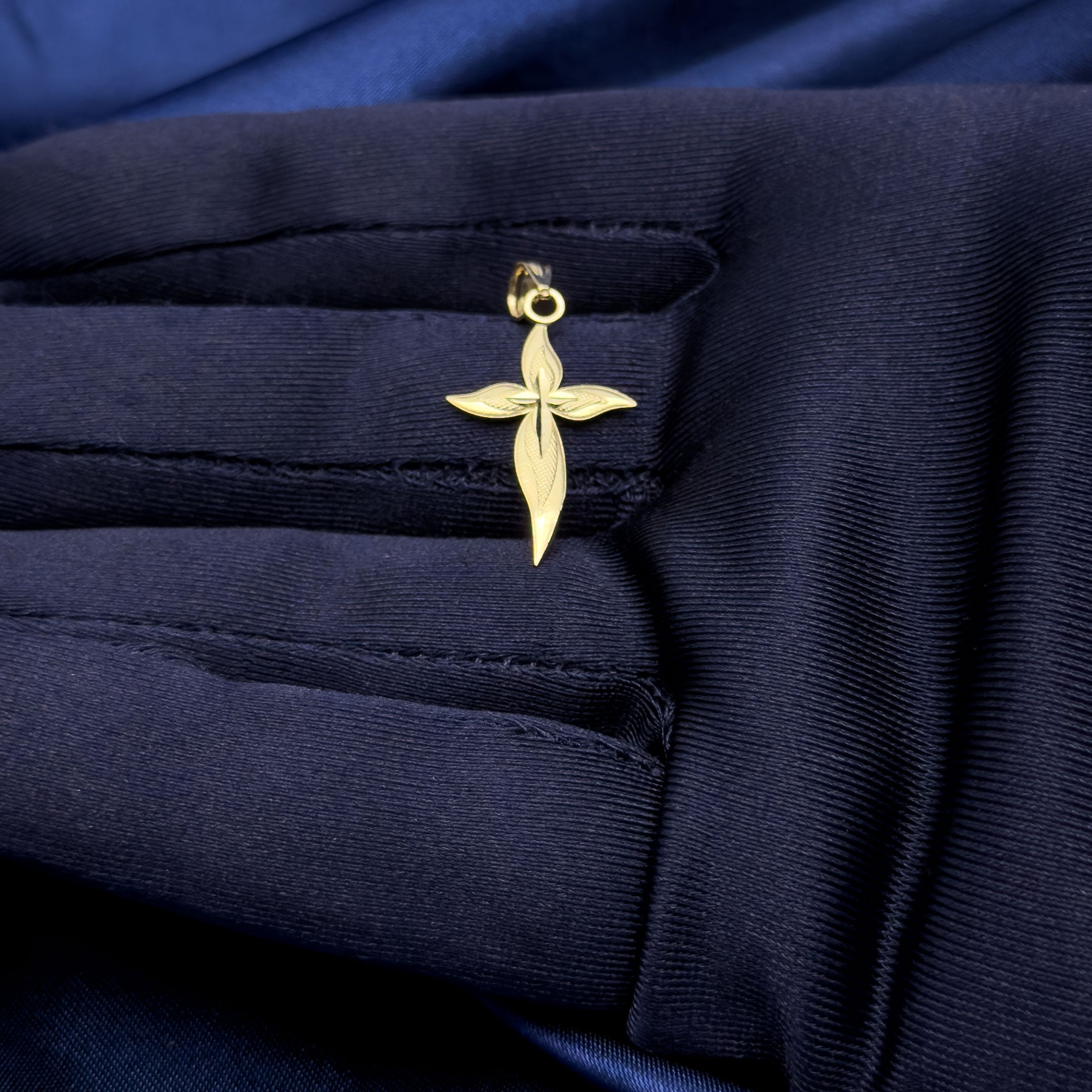 10k gold curvy cross pendant in hand with blue glove