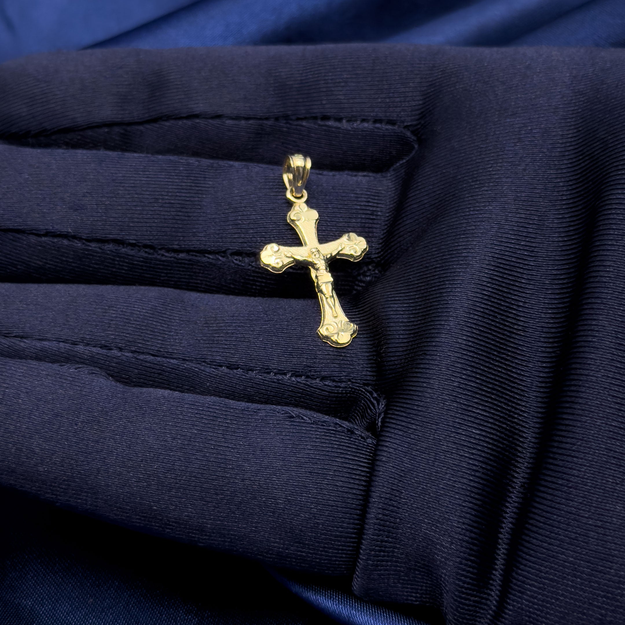 10k yellow gold crucifix trinity style cross pendant in hand with blue glove