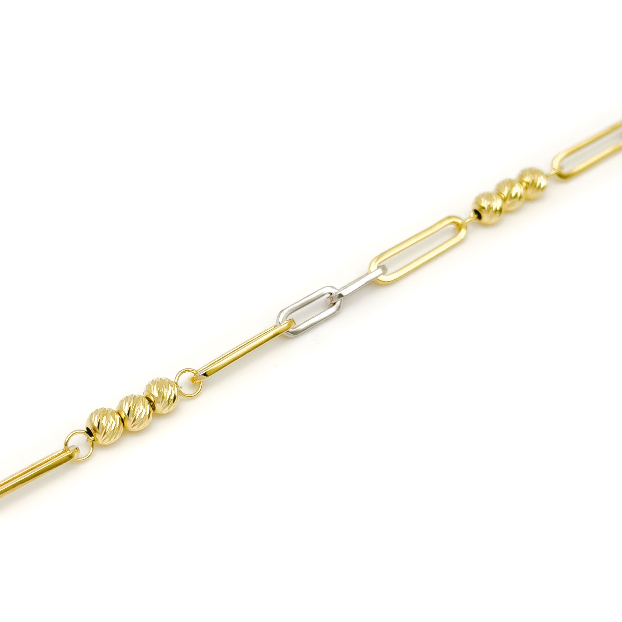 A two-tone yellow gold and white gold paperclip link chain bracelet with triple ball design on a clean white background. close up of links