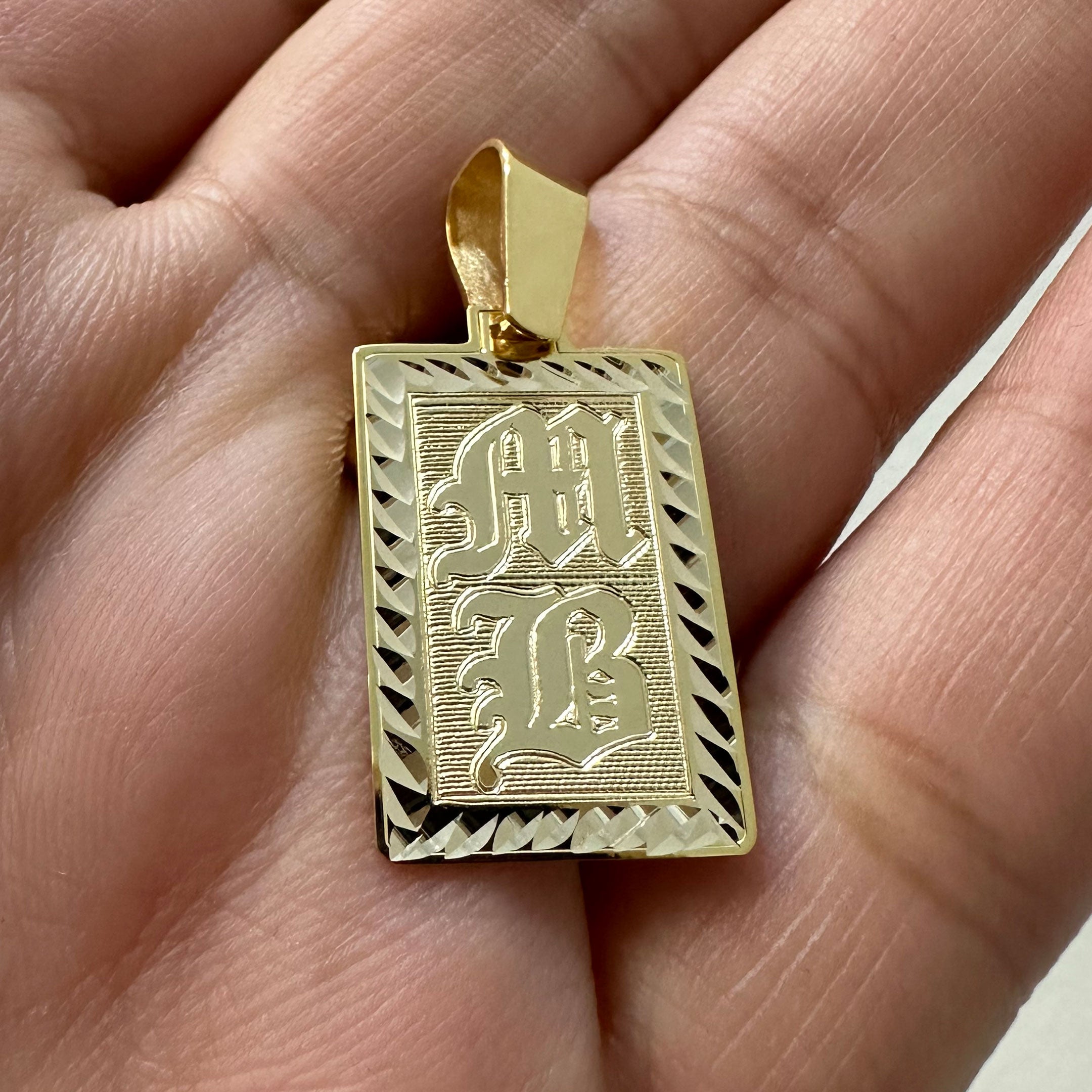 Gold rectangle pendant with diamond cut border and MB engraved in Old English in Hand