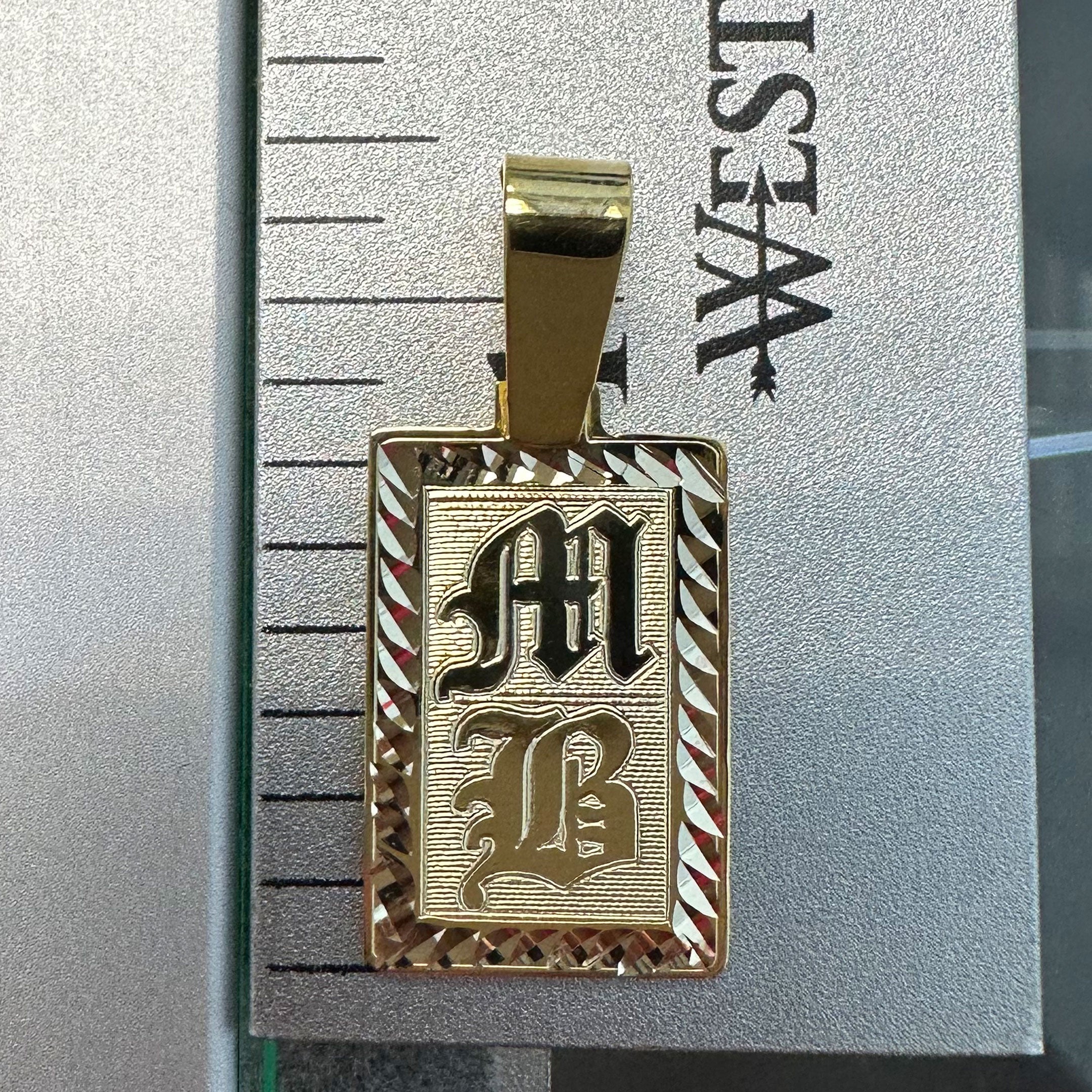 Gold rectangle pendant with diamond cut border and MB engraved in Old English on Ruler