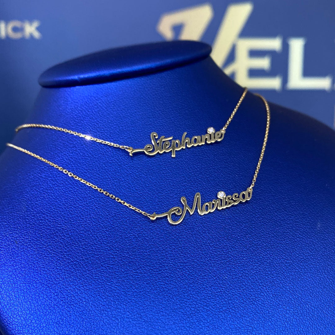 Two personalized mini cursive name pendants with genuine diamond displayed on a blue mannequin bust. Names Stephanie and Marissa. Side