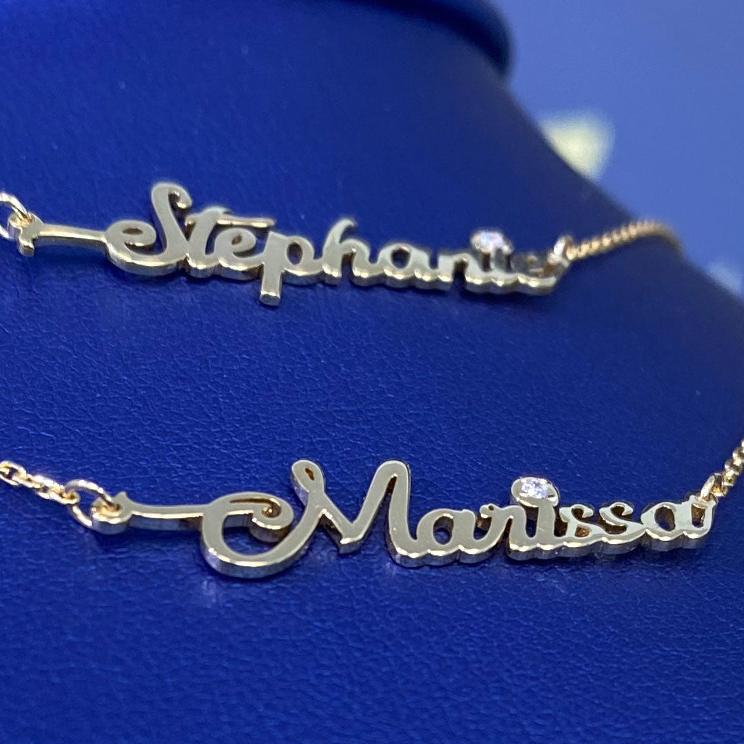 Two personalized mini cursive name pendants with genuine diamond displayed on a blue mannequin bust. Names Stephanie and Marissa. Close